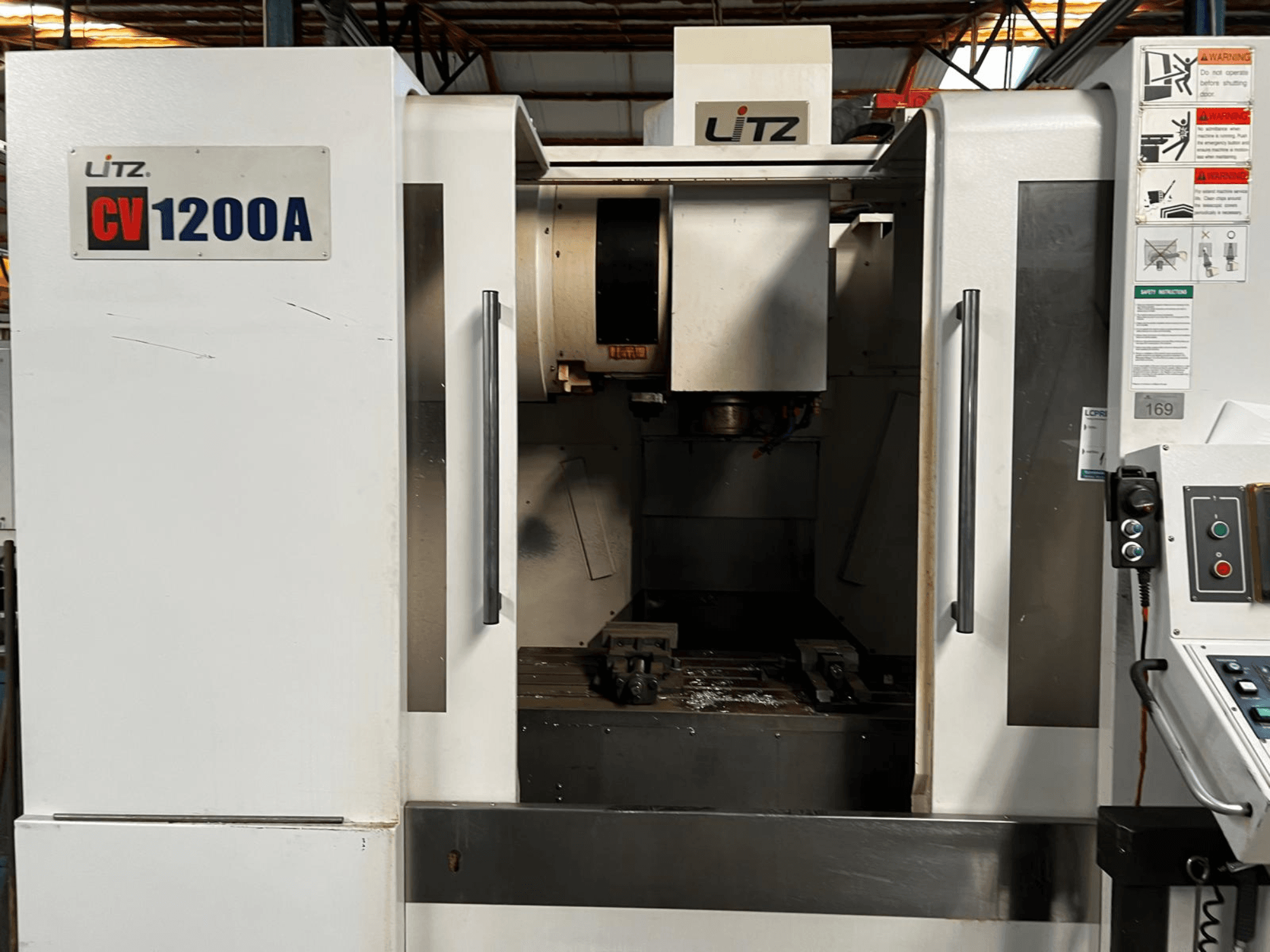 Pionowe centrum obróbcze Litz CV1200A, widok z przodu, przedstawiający panel sterowania, wrzeciono oraz otwarte drzwiczki odsłaniające obszar roboczy.