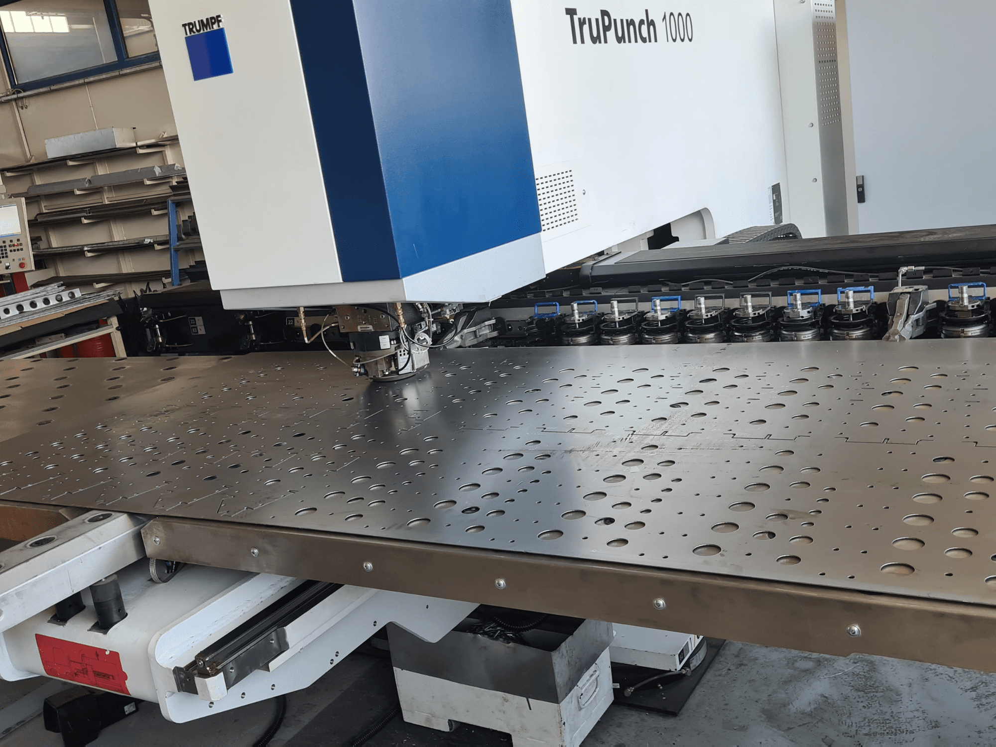 Wykrawarka CNC TRUMPF TruPunch 1000, widok z przodu, przedstawiająca perforowaną blachę oraz ustawienie narzędzi.