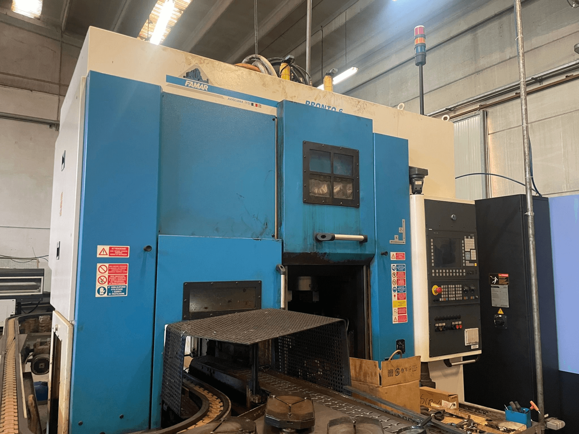 Tokarka pionowa Famar Pronto 6 w warsztacie, widok z boku, pokazujący panel sterowania, funkcje operacyjne i etykiety bezpieczeństwa.