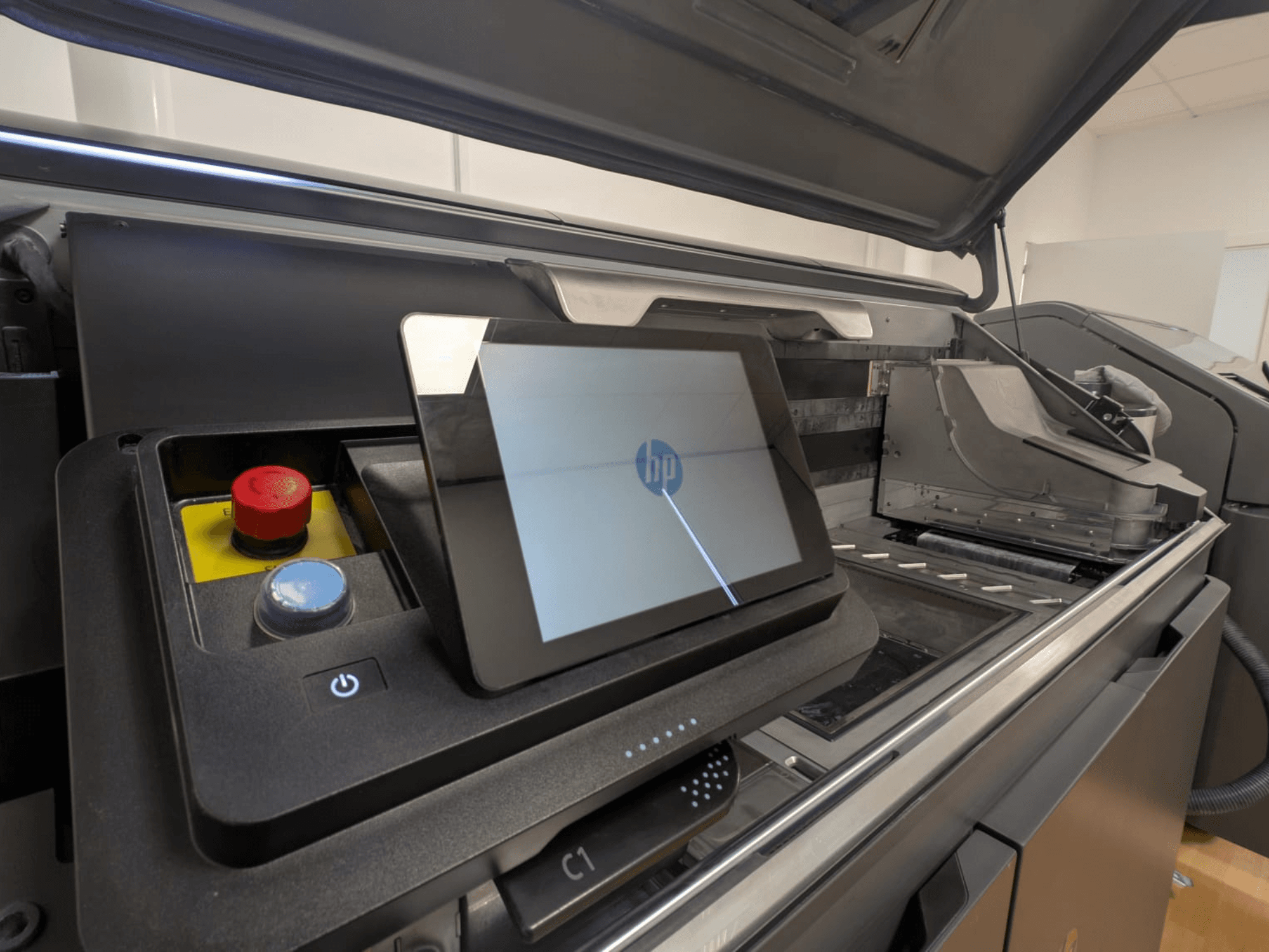 Panel sterowania drukarki HP z wyświetlaczem tabletu, czerwonymi i niebieskimi przyciskami oraz bocznym widokiem elementów wewnętrznych drukarki.