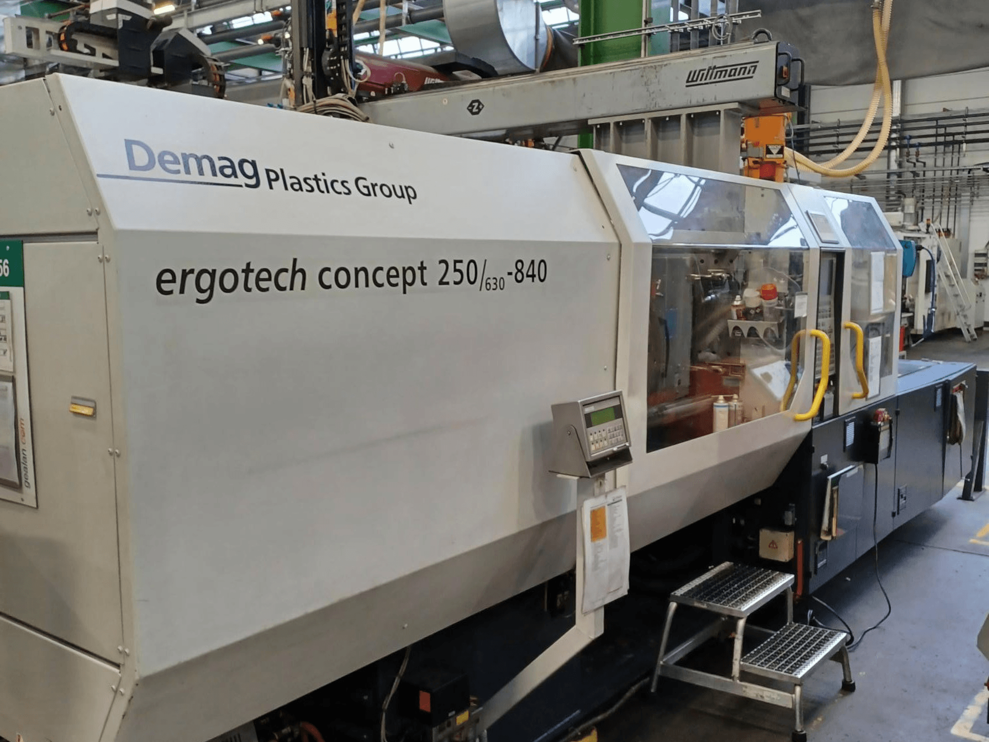 Wtryskarka Demag ergotech concept 250/630-840, widok z przodu, z cyfrowymi elementami sterującymi i przezroczystymi osłonami bezpieczeństwa.