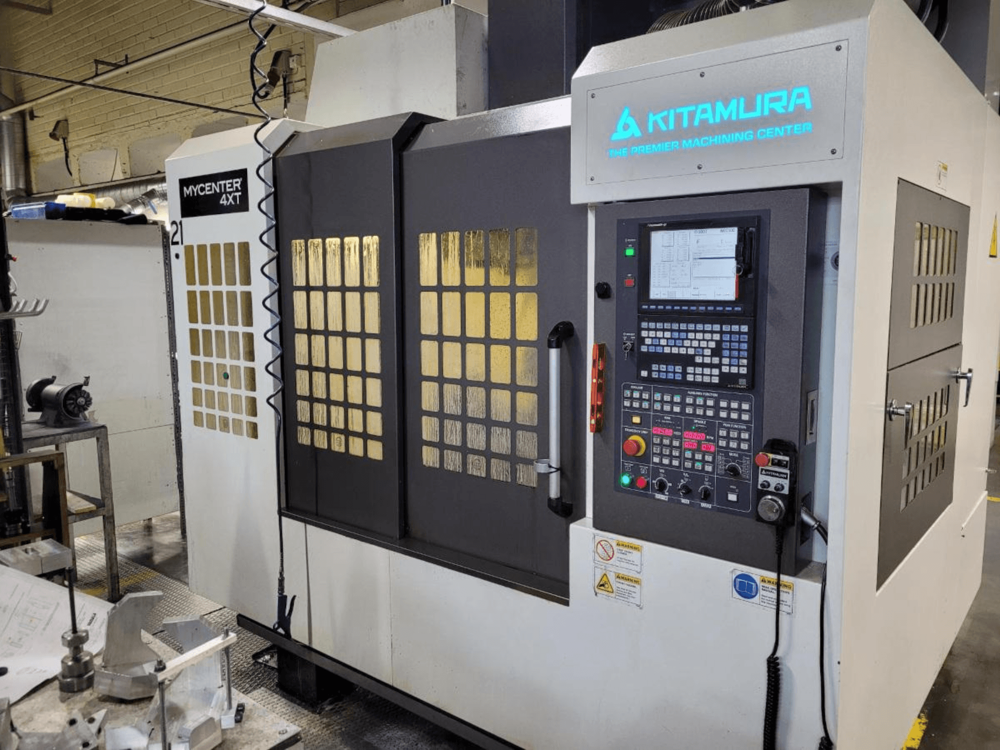 Widok pionowy centrum obróbczego Kitamura Mycenter-4XT z panelem sterowania i podświetlanym logo.
