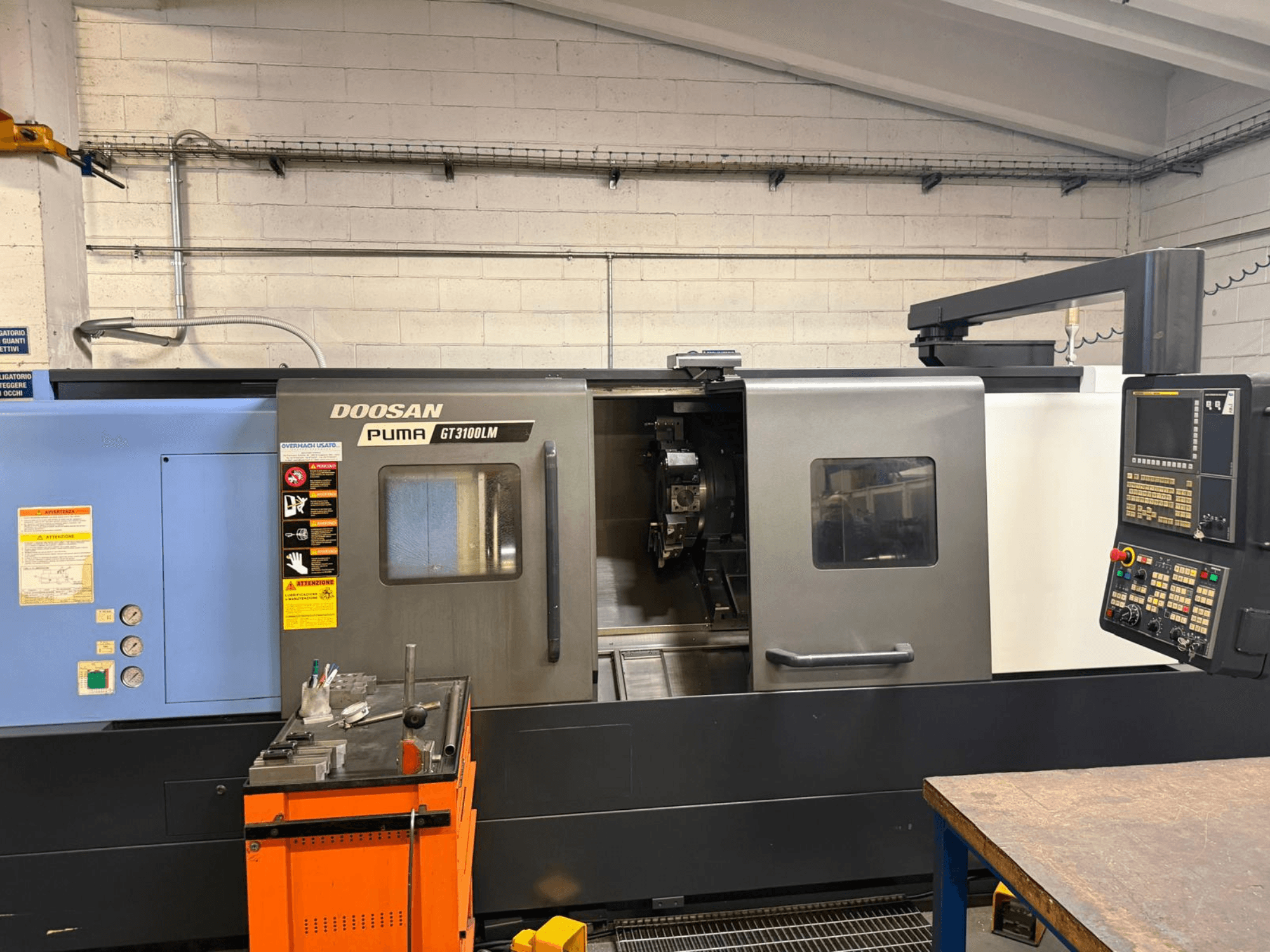 Widok z przodu tokarki poziomej DOOSAN PUMA GT3100LM, przedstawiający panel sterowania i obszar roboczy z narzędziami.
