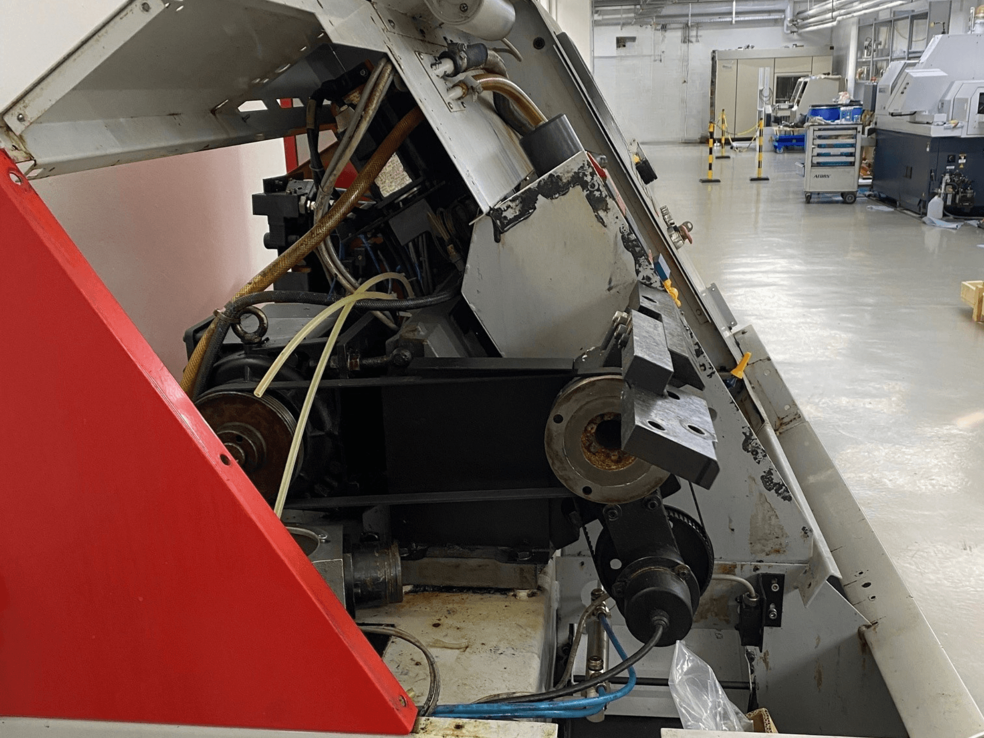 Obracarka pozioma EMCO Emcoturn 325, widok z boku pokazujący elementy napędu i hydrauliki w warunkach przemysłowych.