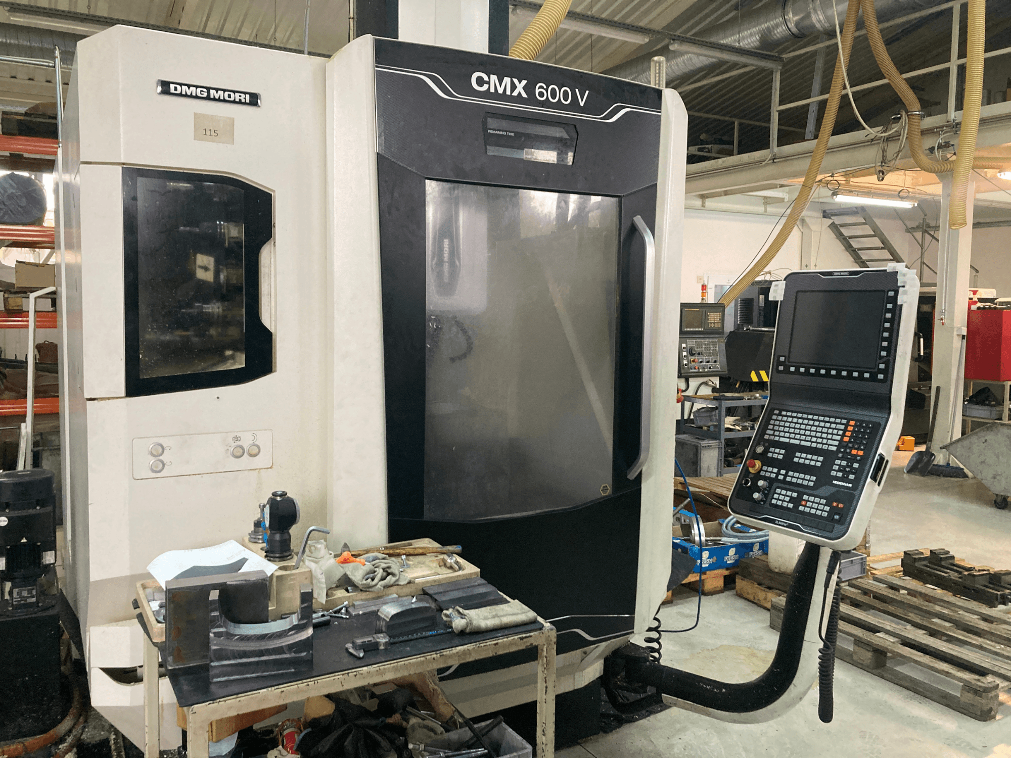 Frezarka DMG MORI CMX 600 V widziana od przodu, z panelem sterowania i stołem roboczym z narzędziami.