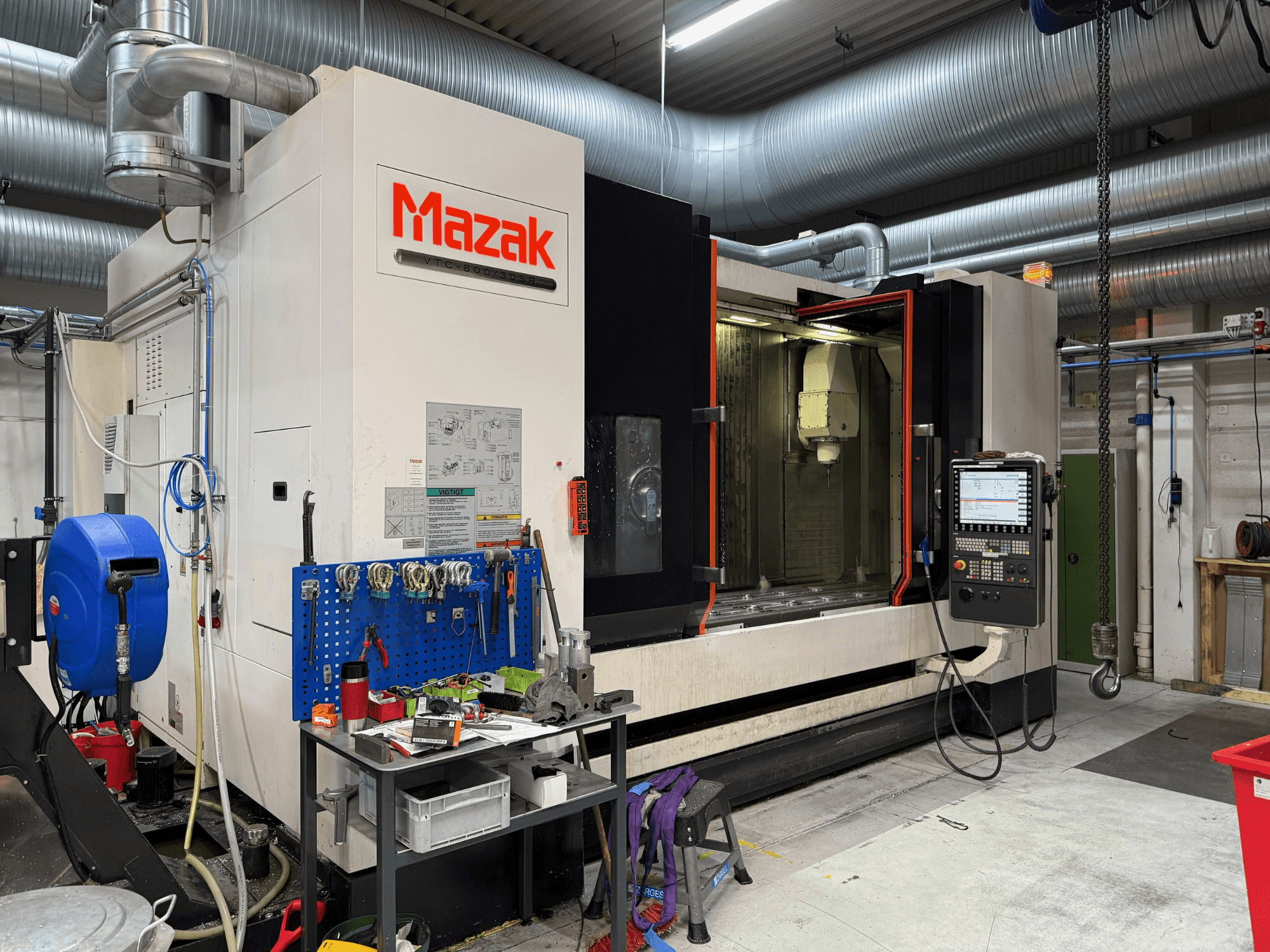Maszyna CNC Mazak w widoku z przodu, z elementami sterującymi, narzędziami i przestrzenią roboczą w środowisku obróbki.