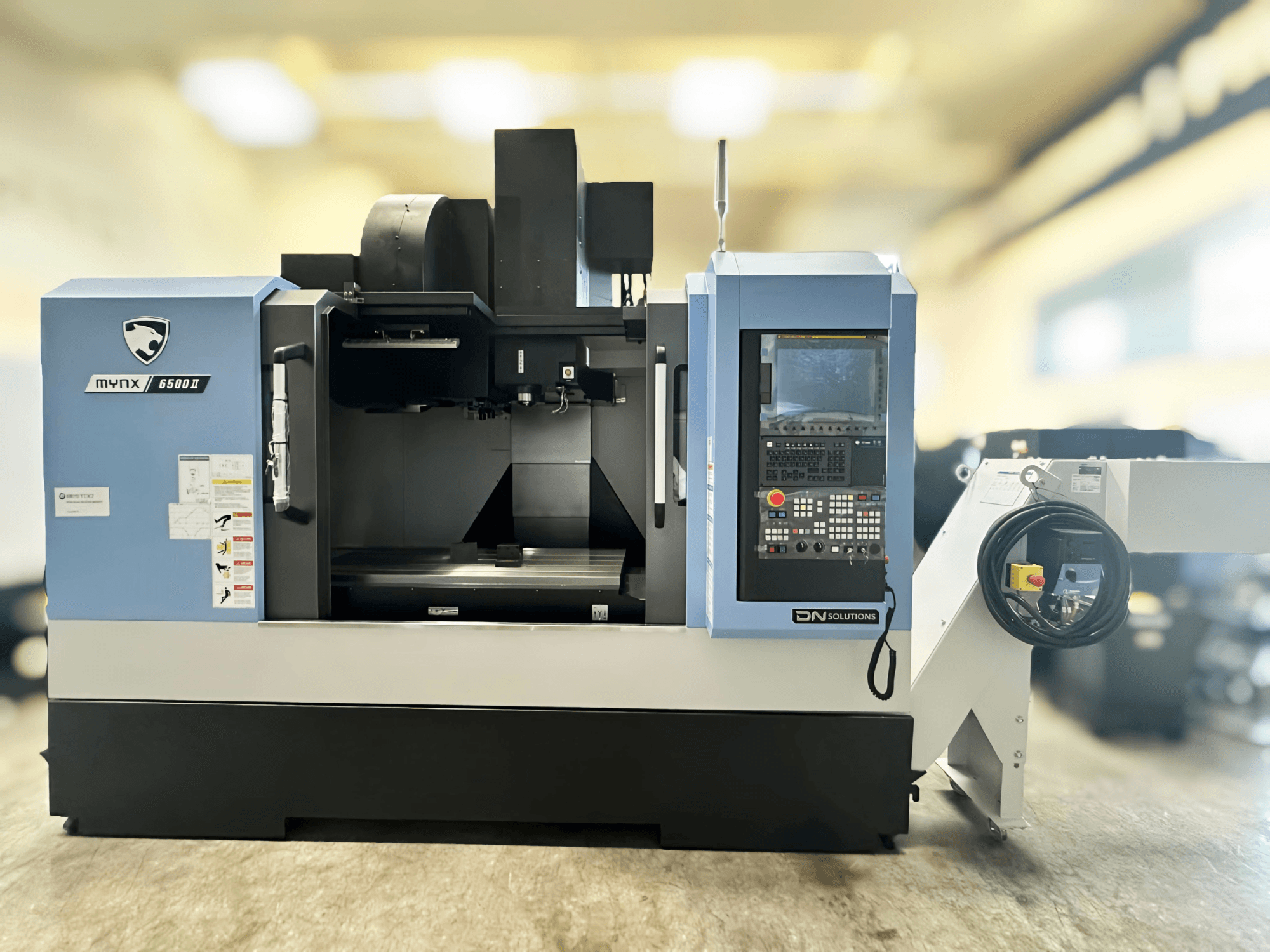 Pionowe centrum obróbcze DN SOLUTIONS MYNX 6500 II, widok z przodu, panel sterowania i otwarty obszar obróbki.