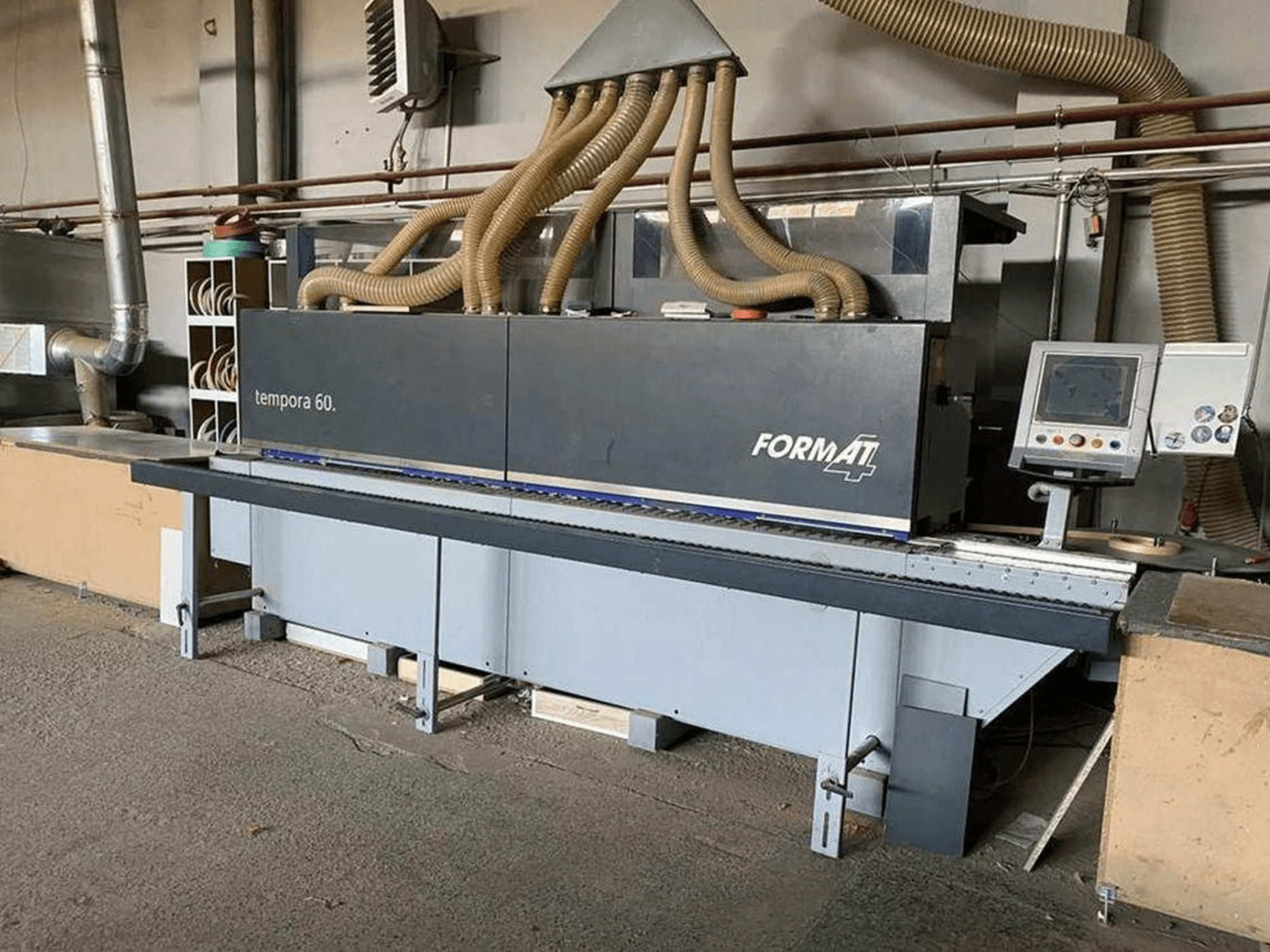 Okleiniarka krawędzi FORMAT4 Tempora 60 w widoku z boku, z wieloma wężami i panelem sterowania z przyciskami i ekranem.