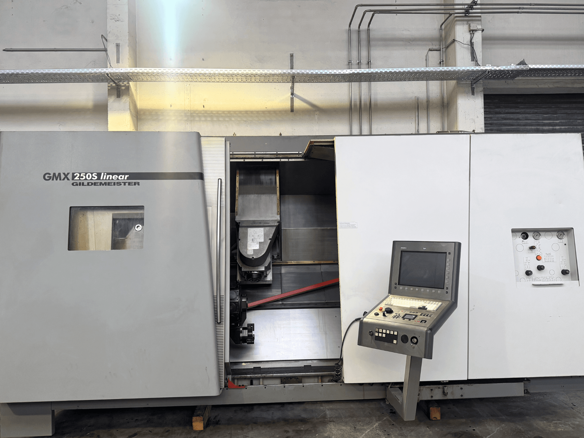Liniowa maszyna CNC Gildemeister GMX 250S, widok z przodu, panel sterowania i otwarty obszar roboczy.