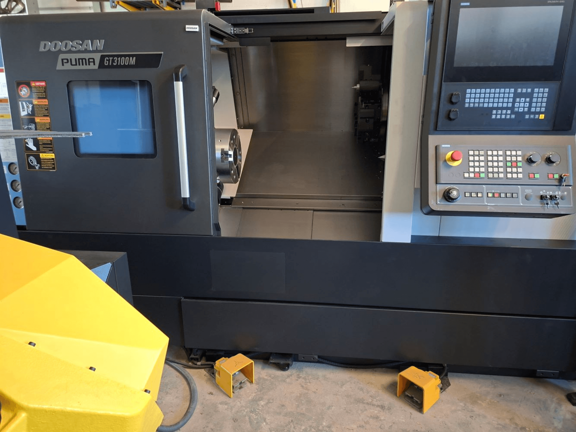 Tokarka pozioma DOOSAN Puma GT 3100 M w widoku z przodu, z panelem sterowania, otwartą wieżą i wewnętrznym obszarem roboczym.