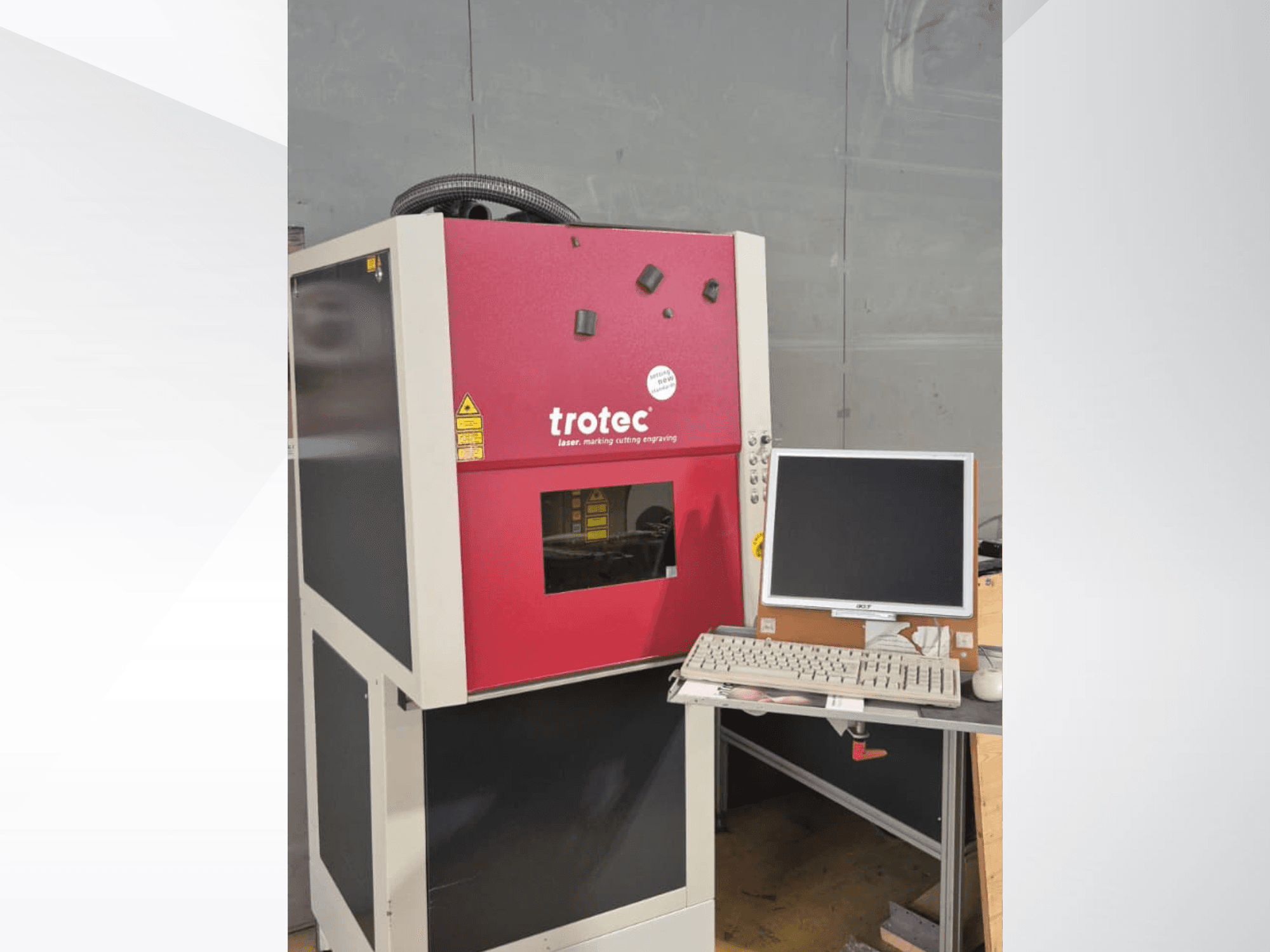 Czerwona stacja robocza Trotec Laser-Work-Station widziana z przodu, wyposażona w monitor i klawiaturę umieszczone na blacie roboczym.