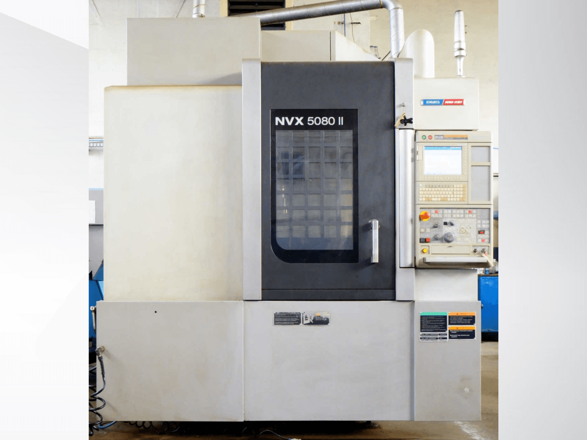 Pionowe centrum obróbcze DMG Mori Seiki NVX 5080 II, widok z przodu, z panelem sterowania i drzwiami z siatki.