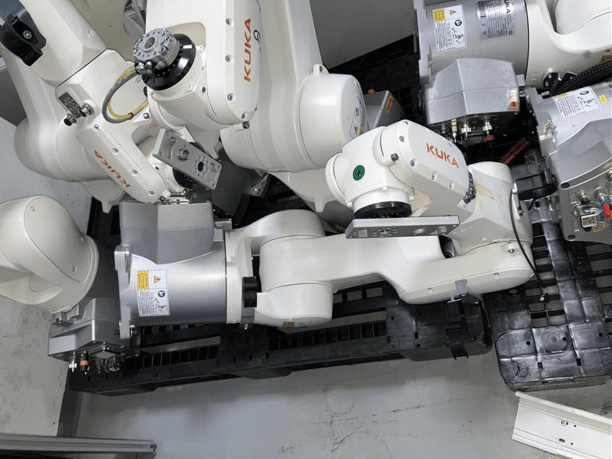 Ramię robota KUKA KR 6 R900 CR w widoku z góry, wyposażone w wiele przegubów i silników, zamontowane na czarnej podstawie z kablami.