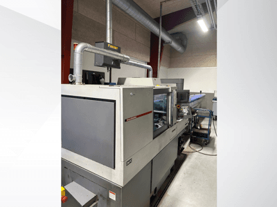 Maszyny przemysłowe marki MVC, widok z boku z widocznym panelem sterowania i kanałami, ustawione w środowisku fabrycznym.