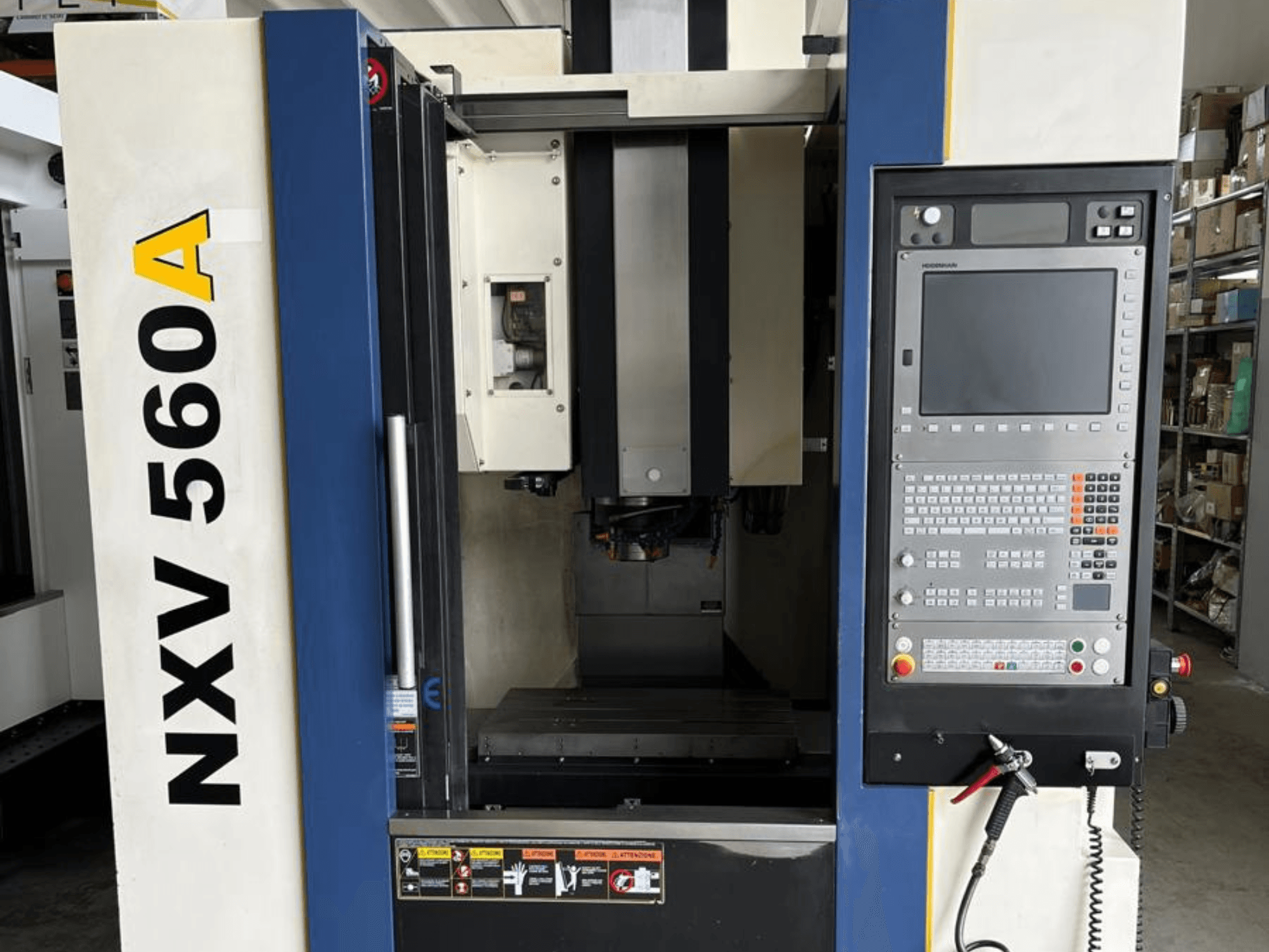 Maszyna CNC NXV 560A widziana od przodu, wyposażona w panel sterowania z przyciskami i wyświetlaczem cyfrowym.