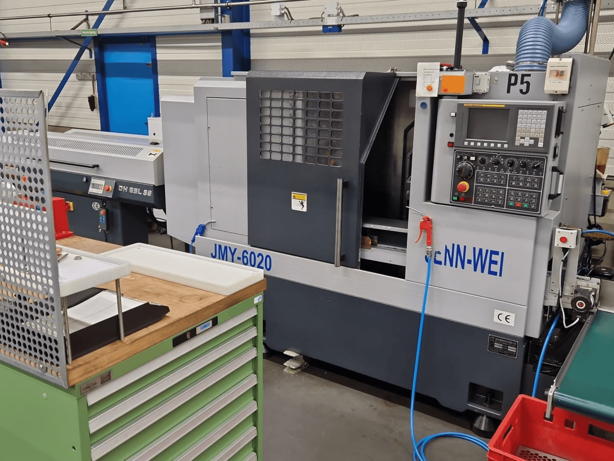 Tokarka CNC, model JMY-6020 firmy cNN-WEI, widziana od przodu. Zawiera panel sterowania, wyłącznik awaryjny i przewód chłodziwa.