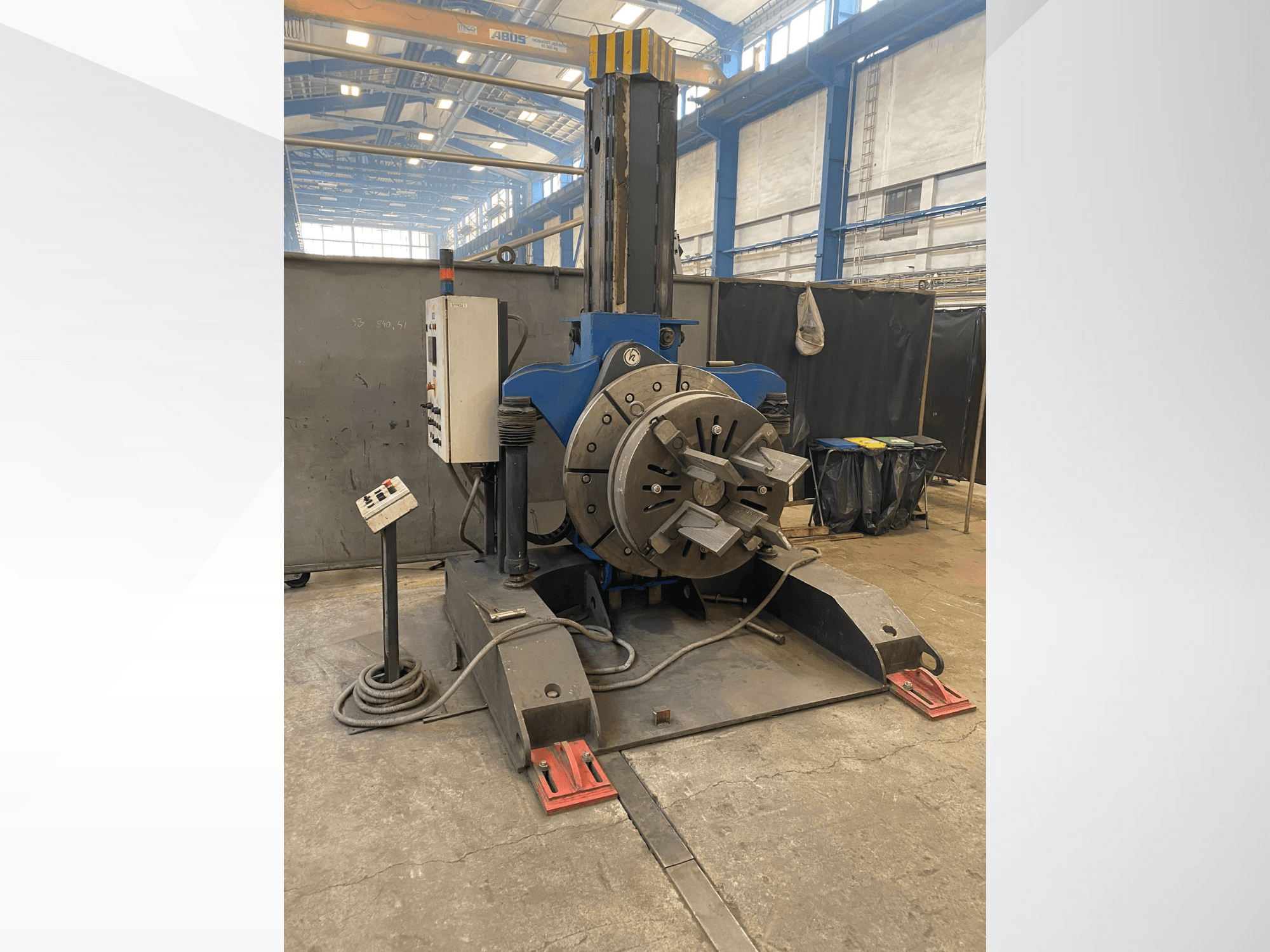 Niebieska tokarka przemysłowa z okrągłą głowicą obrotową i panelem sterowania, widok z boku, w warunkach warsztatowych.