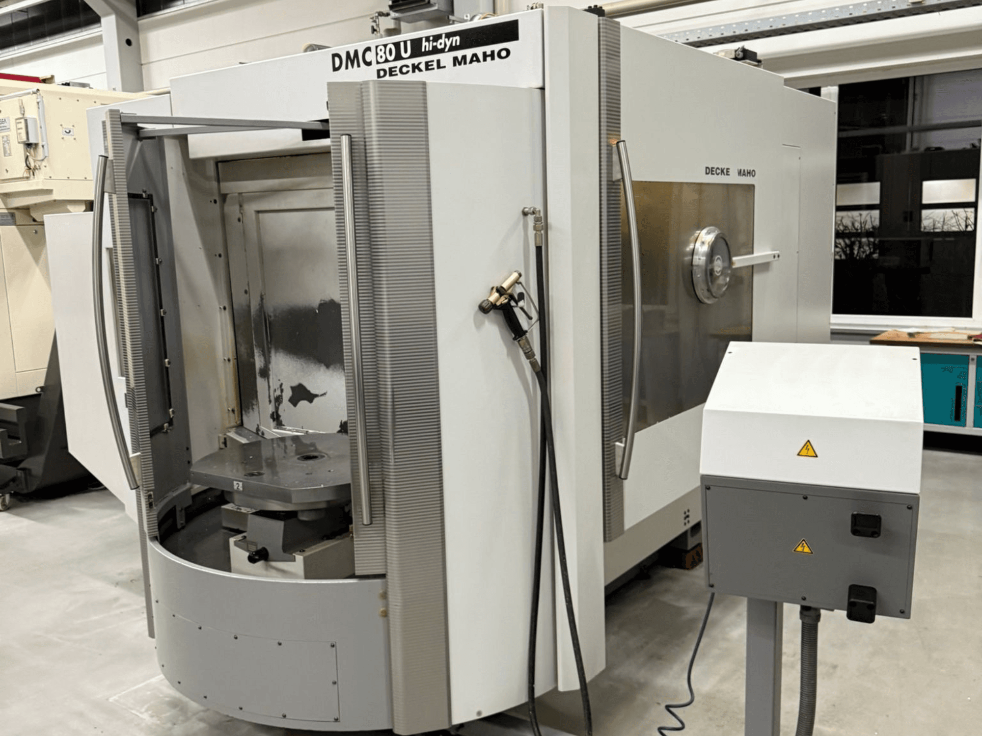 Widok z przodu szybkiej frezarki CNC Deckel Maho DMC 80 U z otwartymi drzwiami dostępowymi i panelem sterowania z boku.