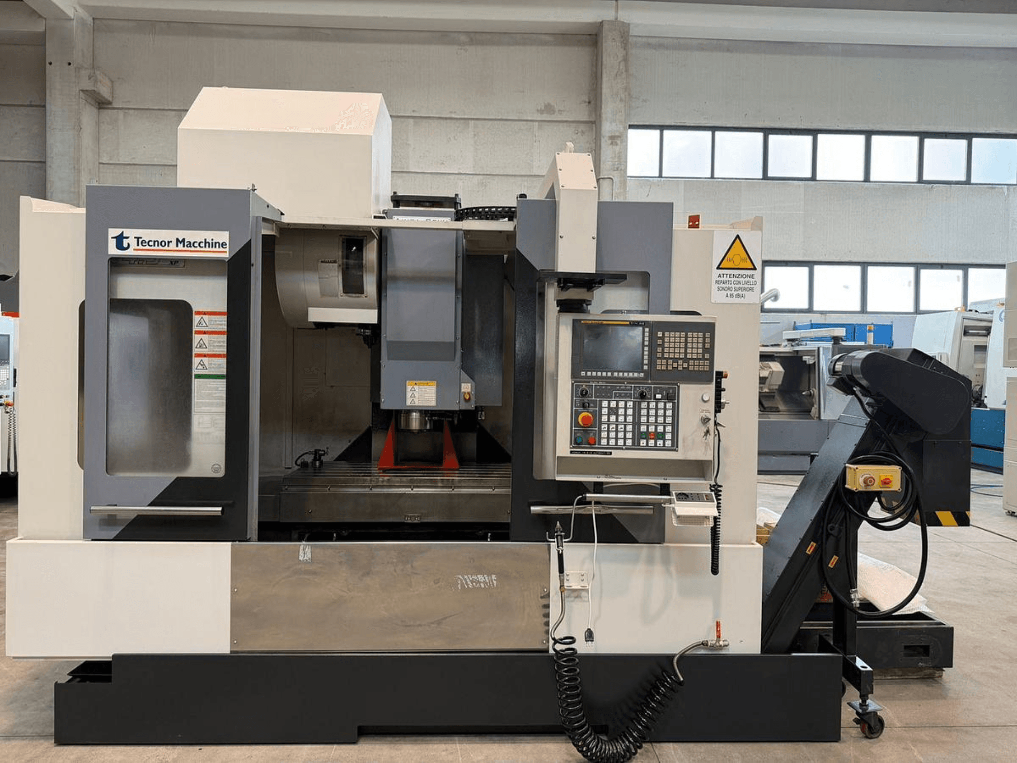 Frezarka CNC Tecnor Machine, widok z przodu, posiada panel sterowania z przyciskami, etykietami ostrzegawczymi i uchwytem na narzędzia.