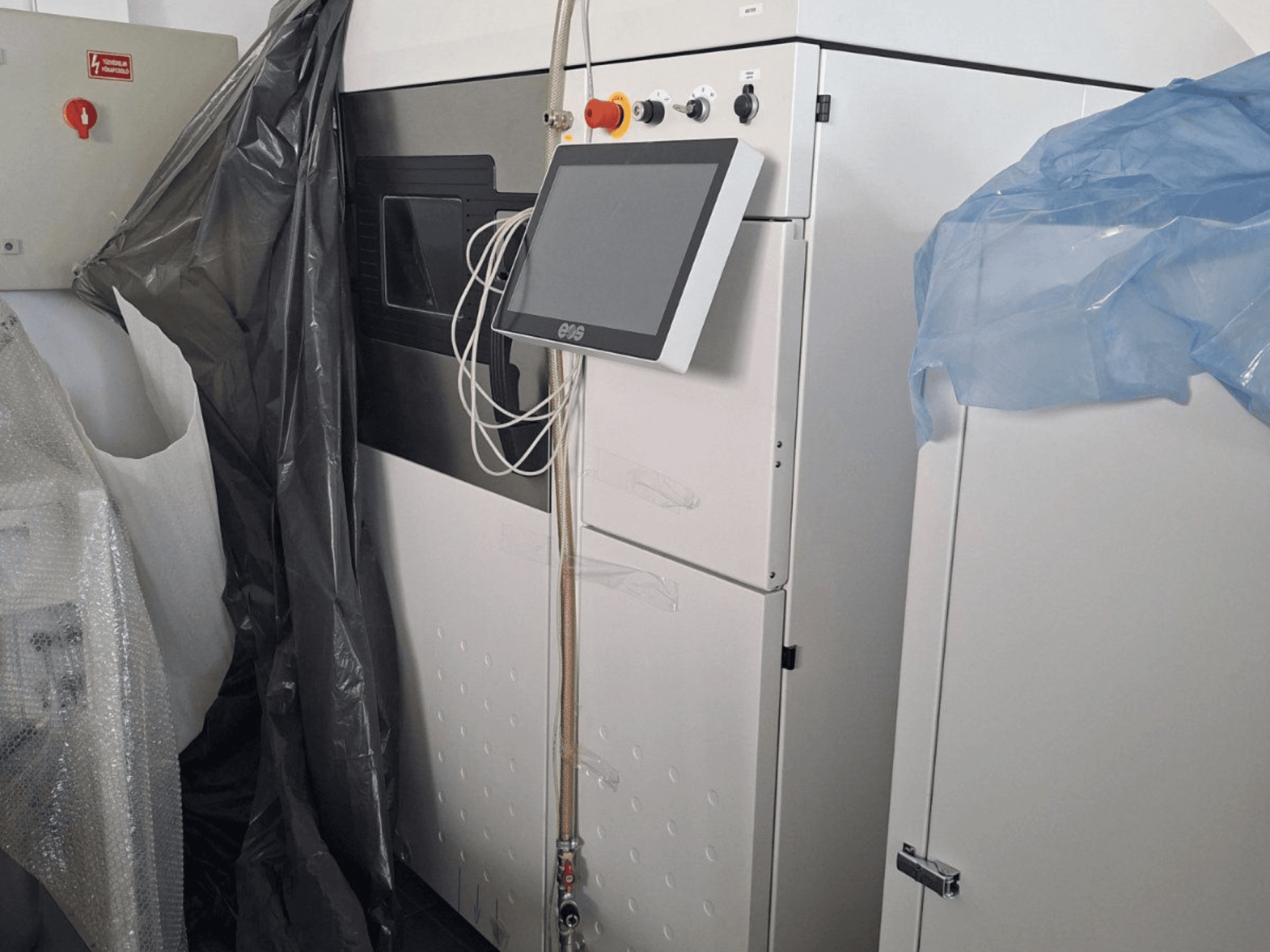 Widok z przodu metalowej drukarki 3D EOS M 290 z ekranem dotykowym, panelem sterowania i osłonami ochronnymi.