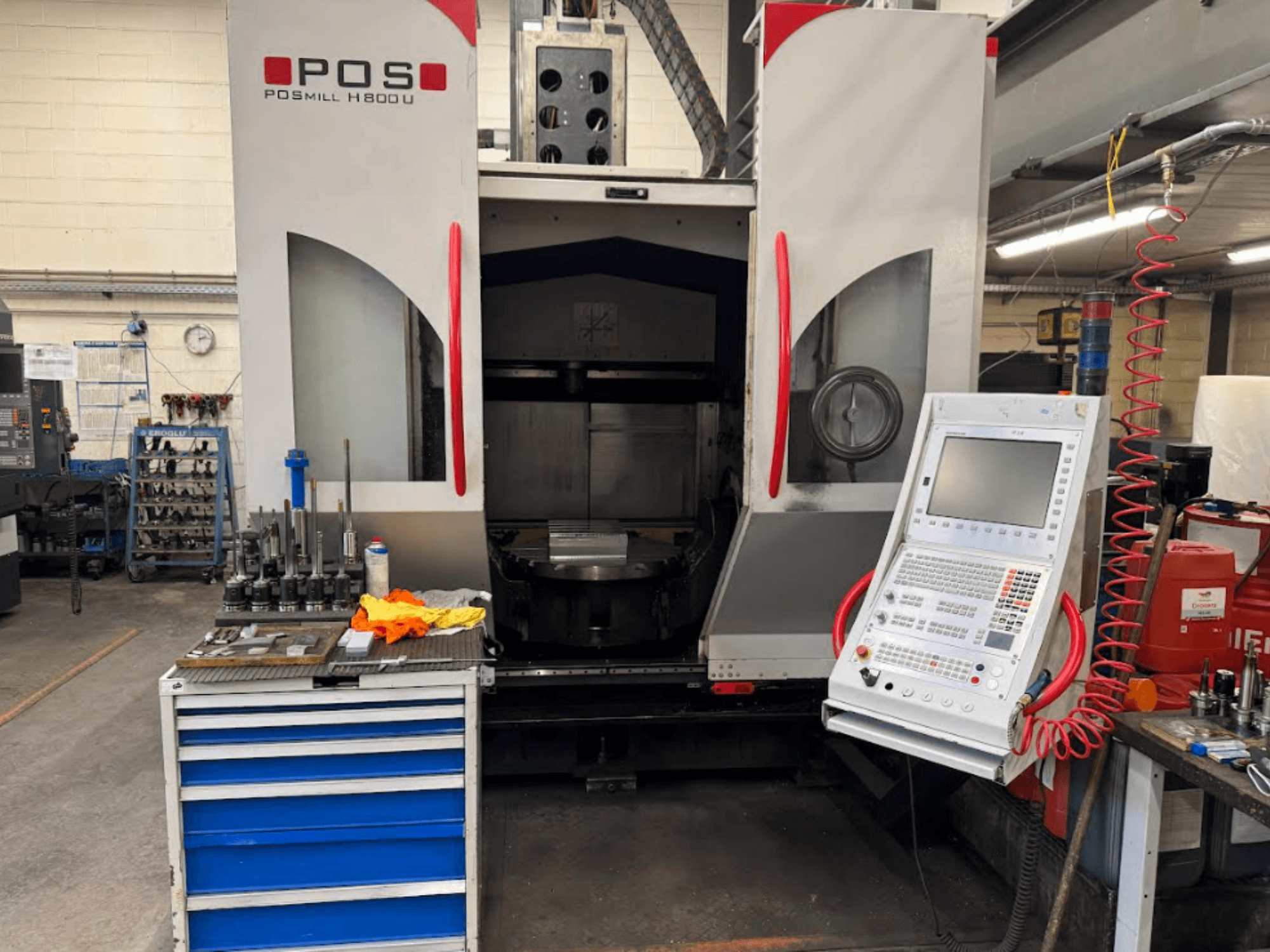 Maszyna CNC POSMILL H800 U widziana od przodu, przedstawiająca panel sterowania i obszar roboczy z narzędziami i wyposażeniem w pobliżu.