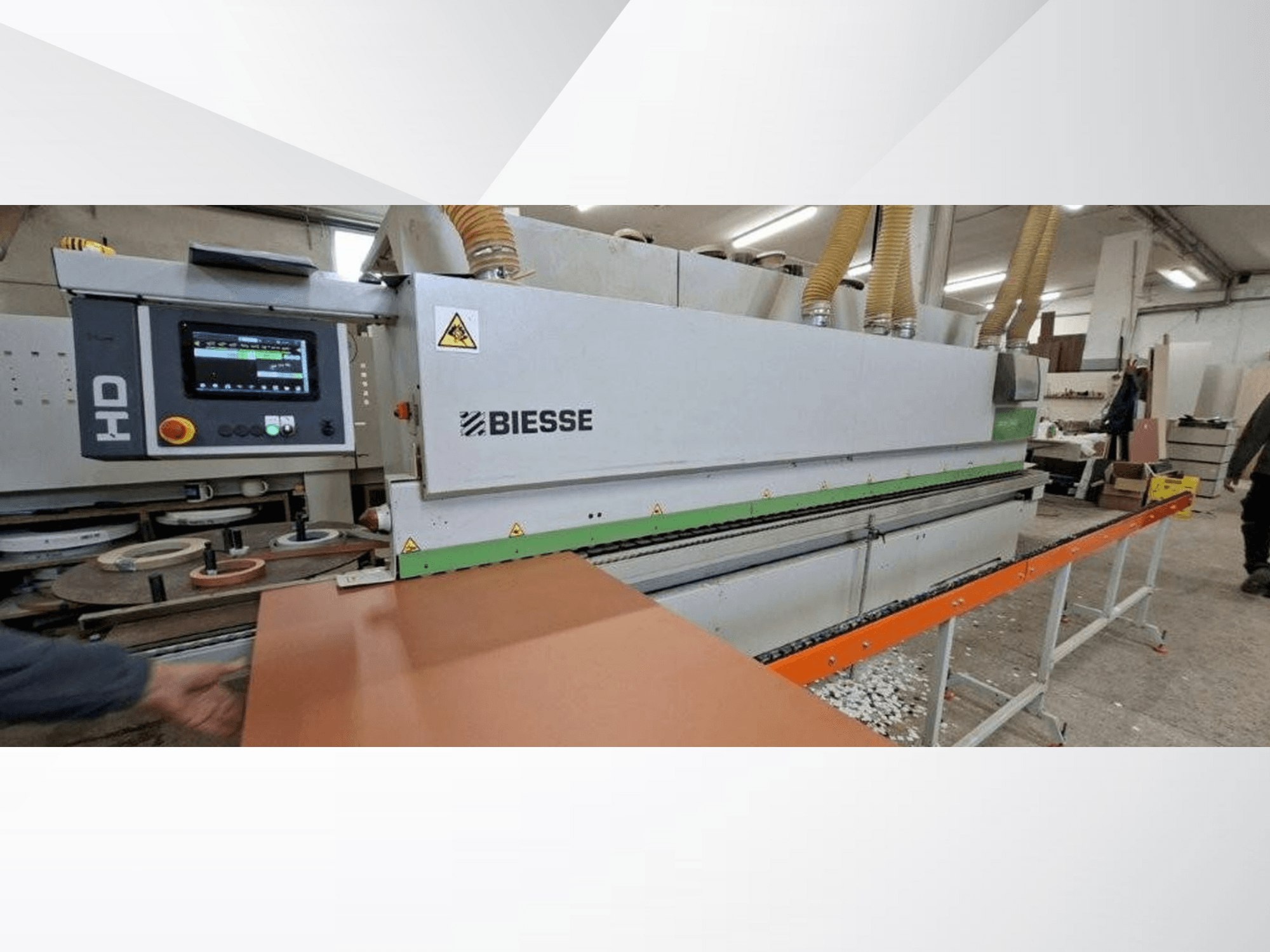 Okleiniarka BIESSE JADE 340 w warsztacie, widok z przodu z cyfrowym panelem sterowania i pomarańczowym stołem podającym.