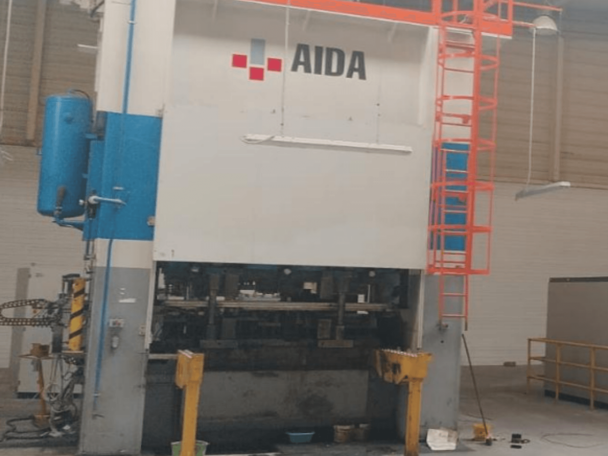 Mechaniczna prasa tłocząca AIDA 315/2MR/LD/TE3, widok z przodu, z elementami hydraulicznymi i drabiną bezpieczeństwa.