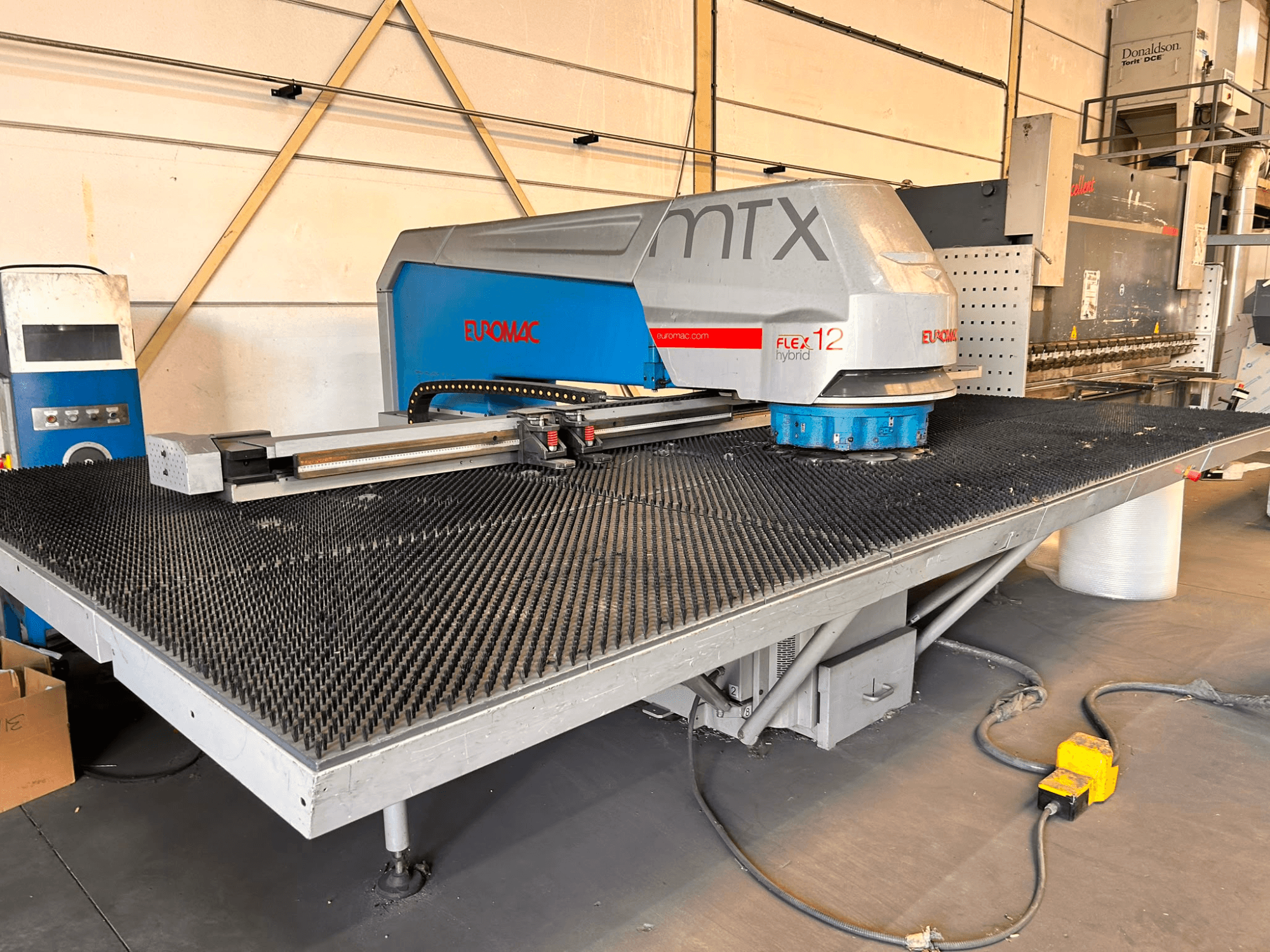 Wykrawarka CNC Euromac MTX FLEX 12, widok z przodu, wyposażona w duży stół perforowany i panel sterowania.