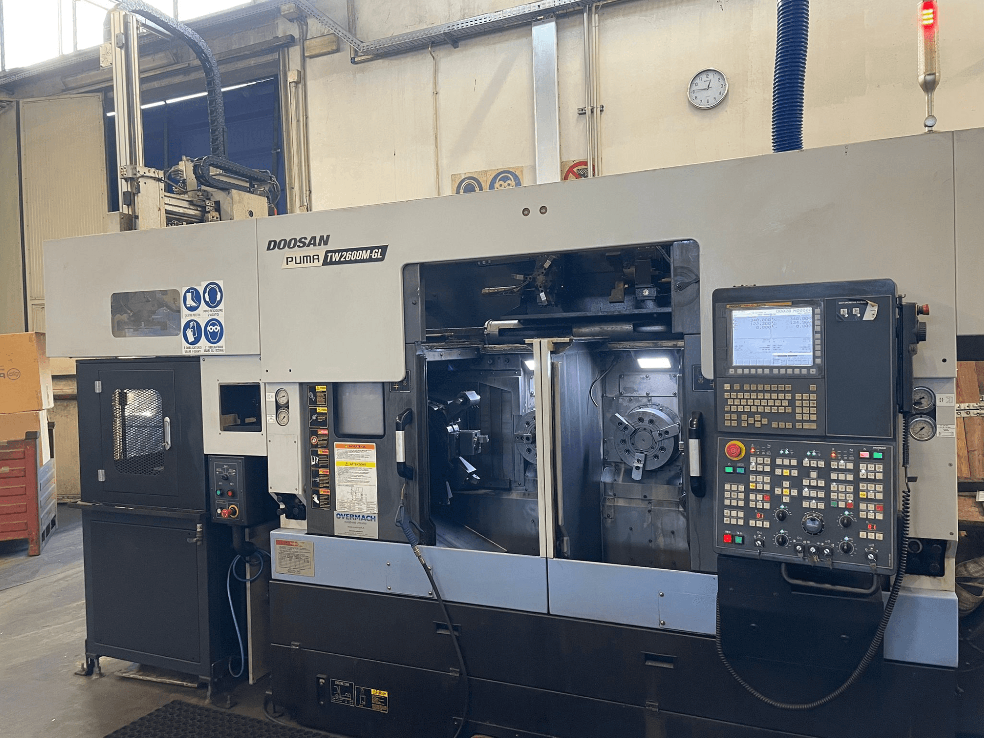 Tokarka CNC Doosan Puma TW2600M GL, widok z przodu, z cyfrowym panelem sterowania i wnętrzem maszyny z uchwytami narzędziowymi.