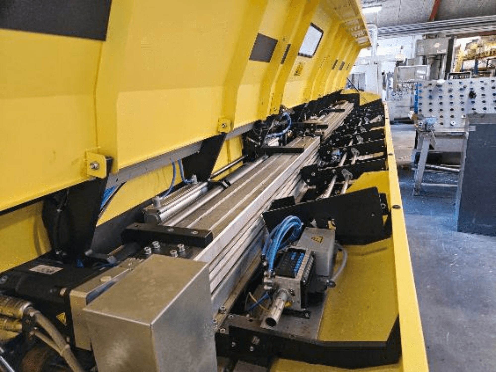 Zbliżenie na żółtą maszynę hydrauliczną z metalowymi elementami i gąsienicami przenośnika, z wężami i częściami elektronicznymi.