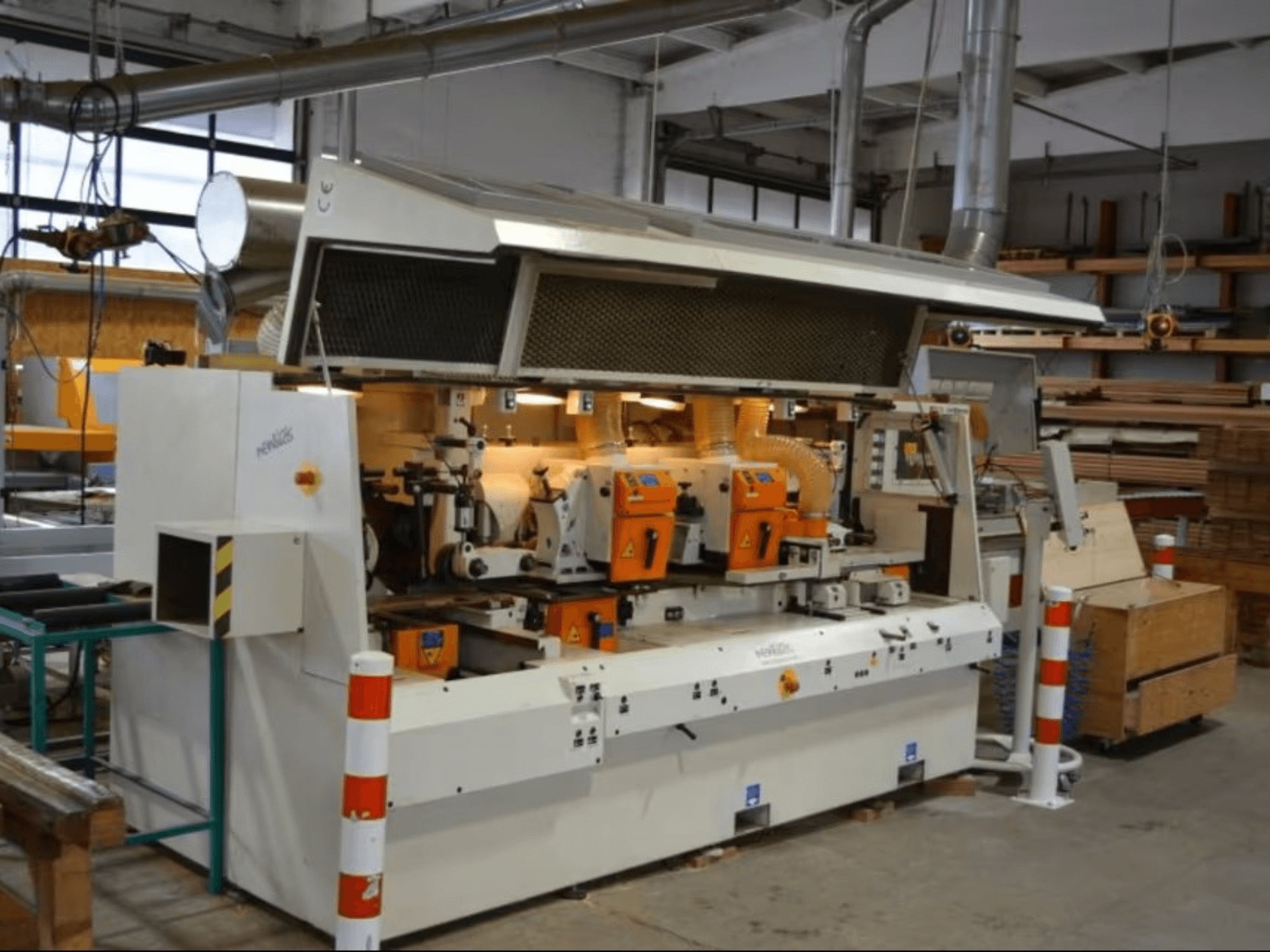 Maszyna do obróbki drewna PENIGAS, widok z przodu, wyposażona w dwie pomarańczowe głowice tnące i system odsysania pyłu w warunkach warsztatowych.