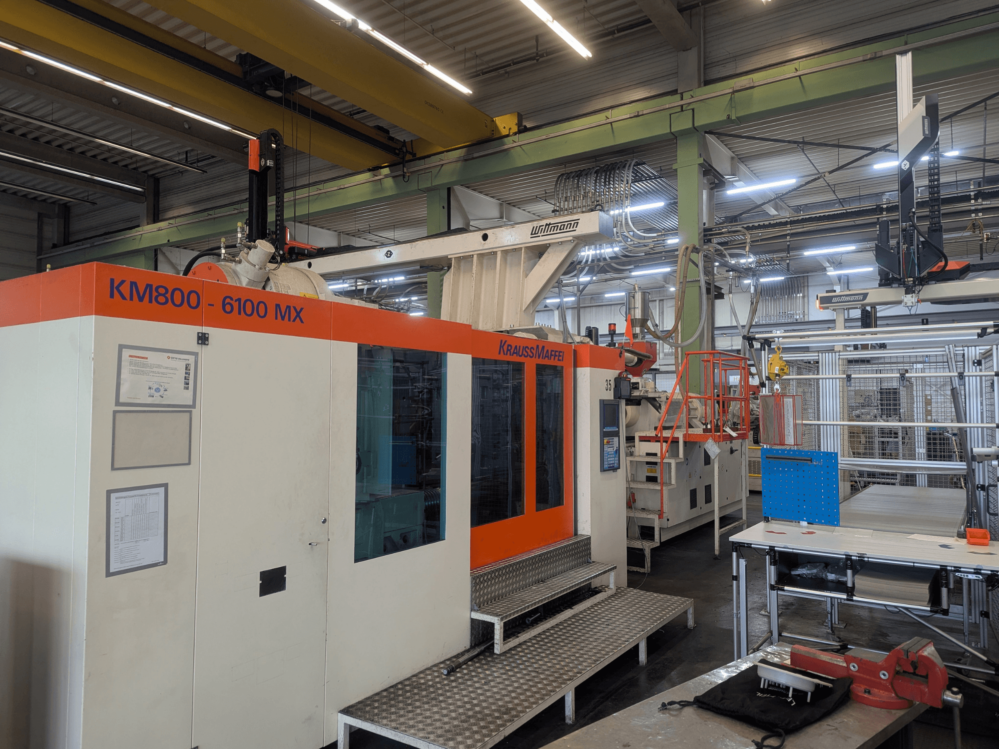 Hydrauliczna wtryskarka Krauss Maffei KM 800-6100MX, widok z przodu, panel sterowania i konfiguracja przemysłowa.