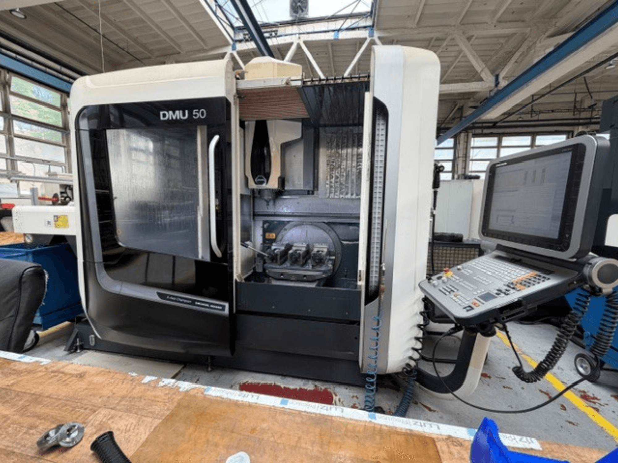 Pionowe centrum obróbcze DMG MORI DMU 50 trzeciej generacji widziane z przodu, z otwartymi drzwiami, widocznym panelem sterowania CNC oraz przestrzenią roboczą wewnątrz.