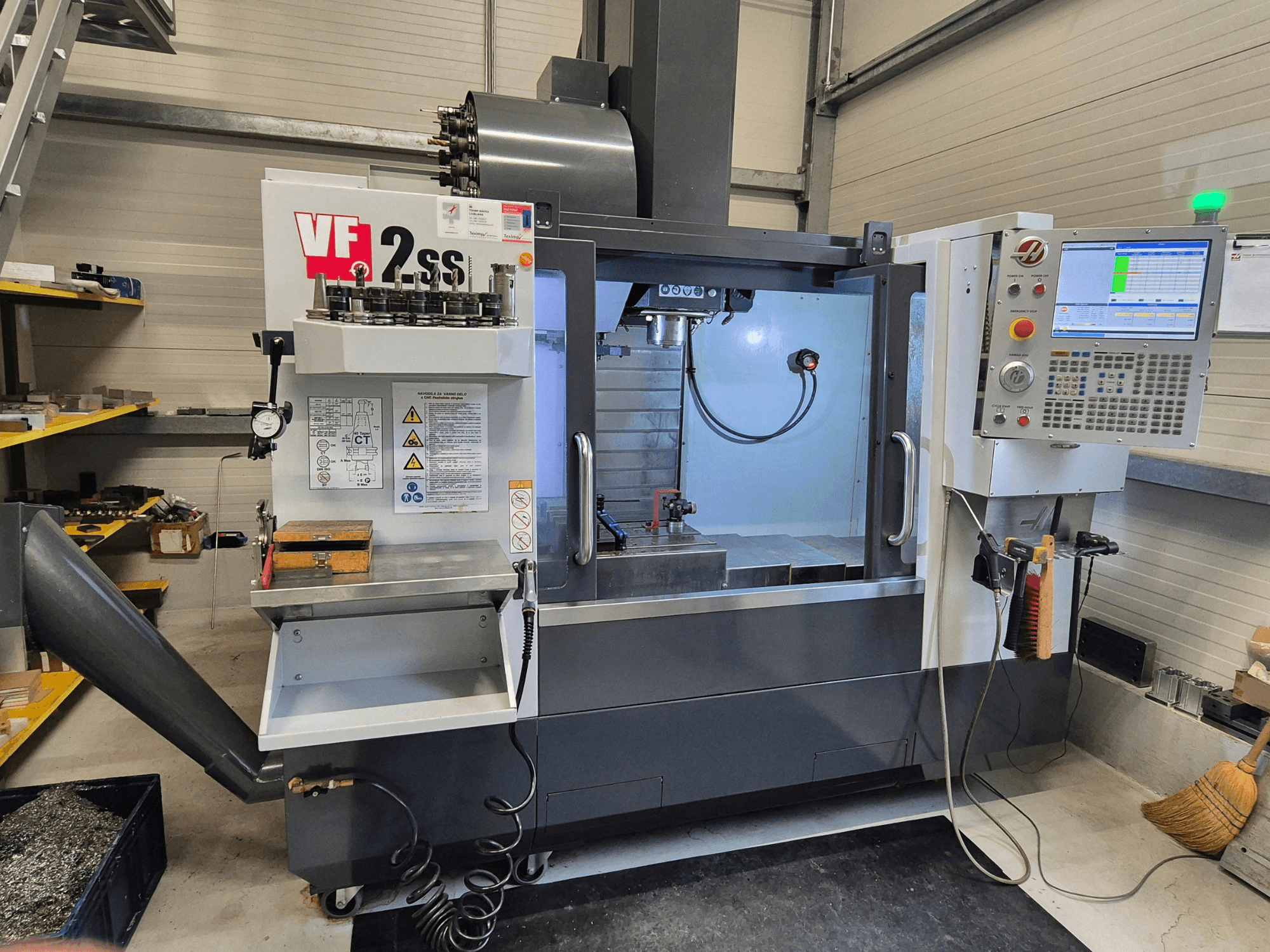 Pionowe centrum obróbcze HAAS VF2 SS-EU w widoku z przodu, z elementami sterującymi, wrzecionem i obszarem obróbki.