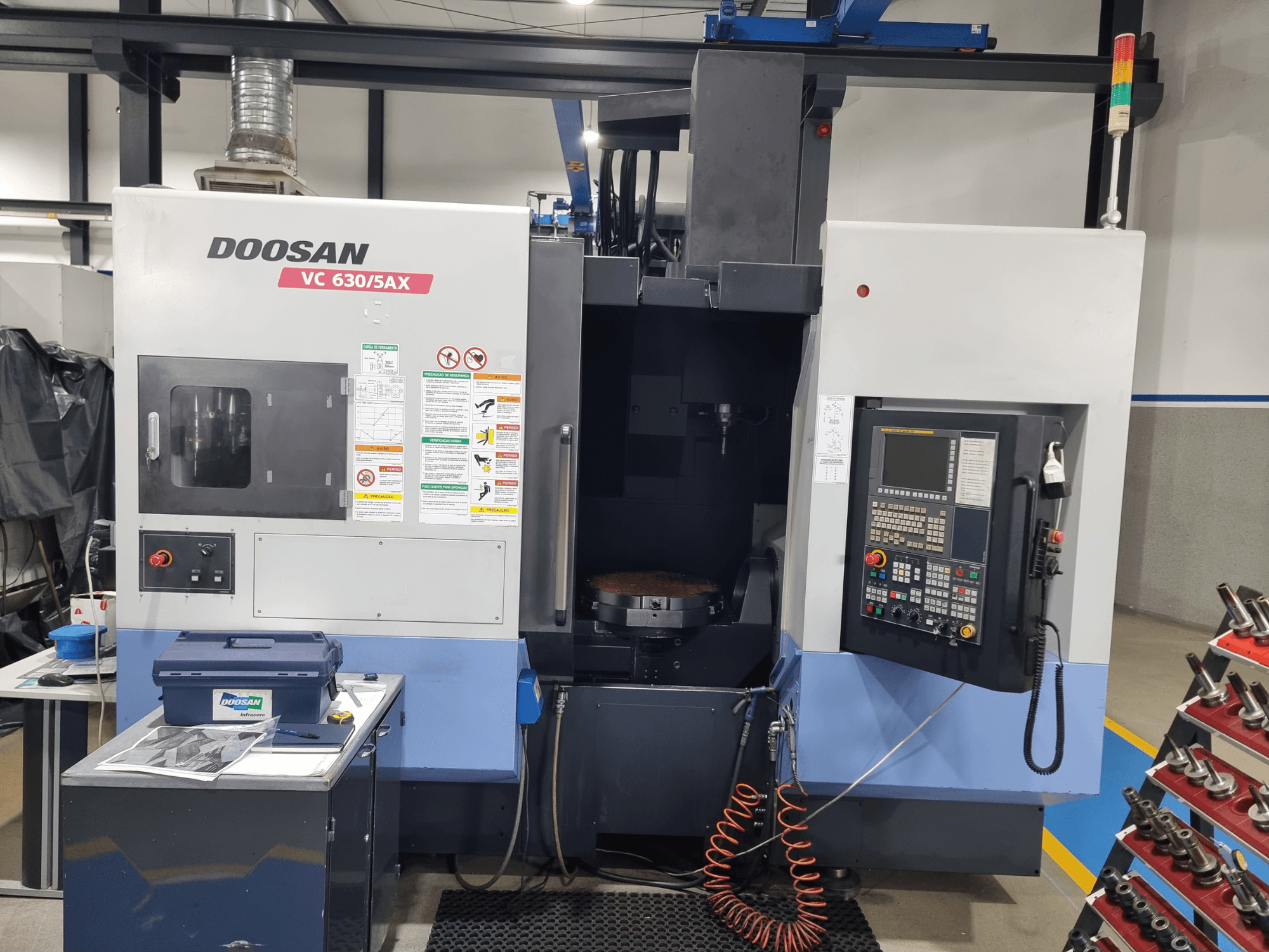 Uniwersalne centrum obróbcze DOOSAN VC 630/5AX – widok z przodu przedstawiający panel sterowania, obszar obróbki oraz elementy zabezpieczające.