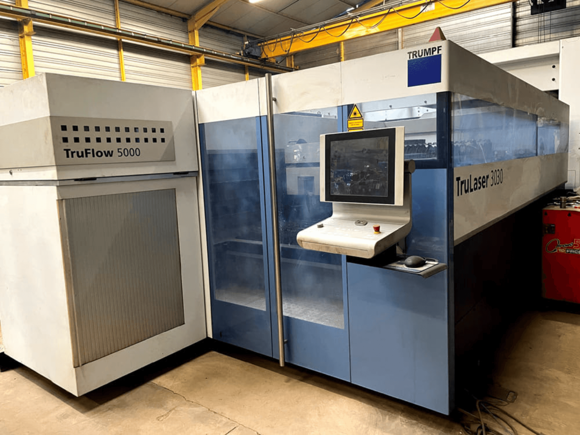 Maszyna do cięcia laserowego CO₂ TRUMPF TruLaser 3030 – widok z przodu, z panelem sterowania i sąsiadującym urządzeniem TruFlow 5000.