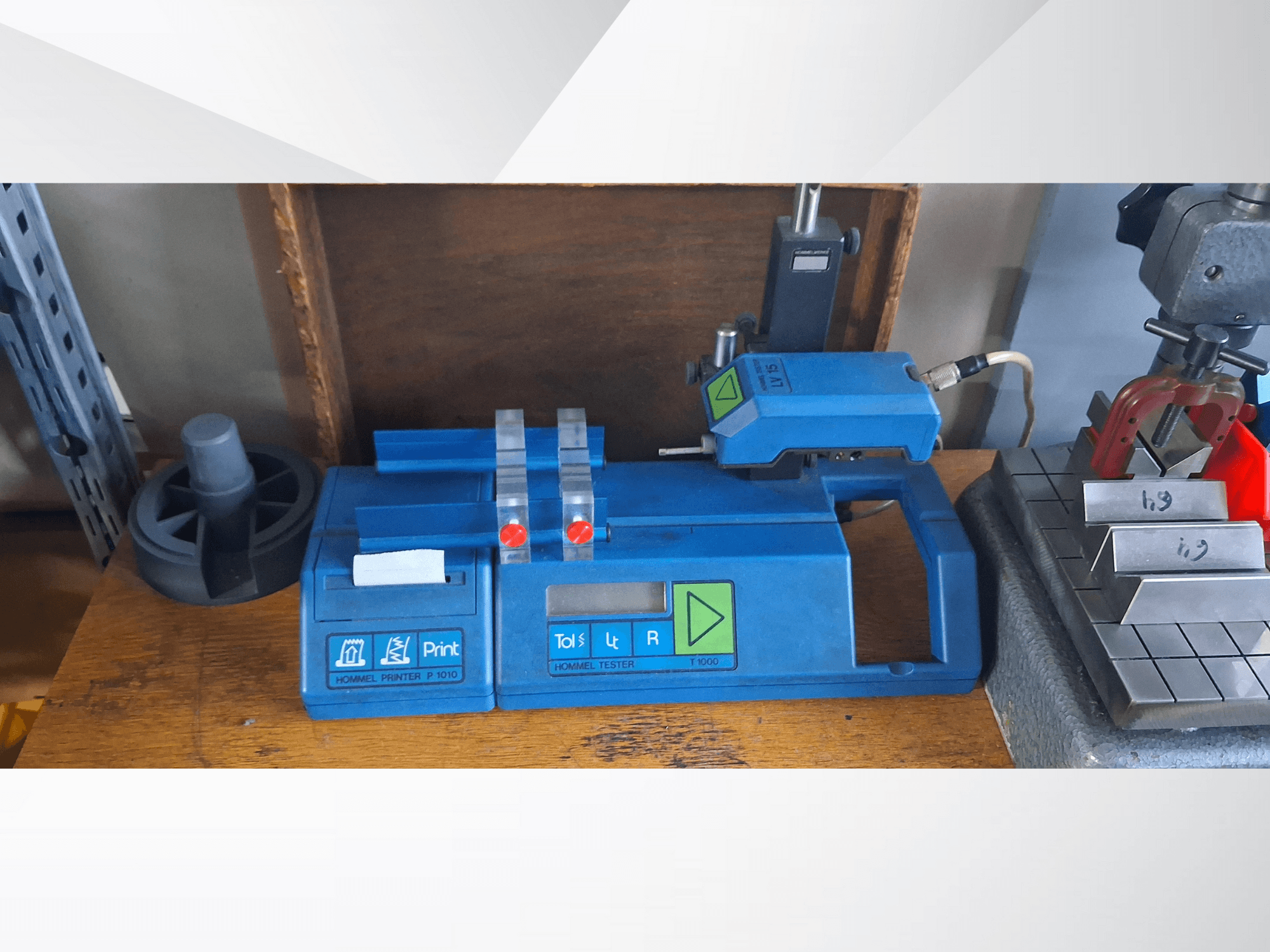 Drukarka Hommel P 1010 i tester T1000 w widoku z boku, z niebieską obudową, przyciskami i czerwonymi wskaźnikami, na stole warsztatowym.