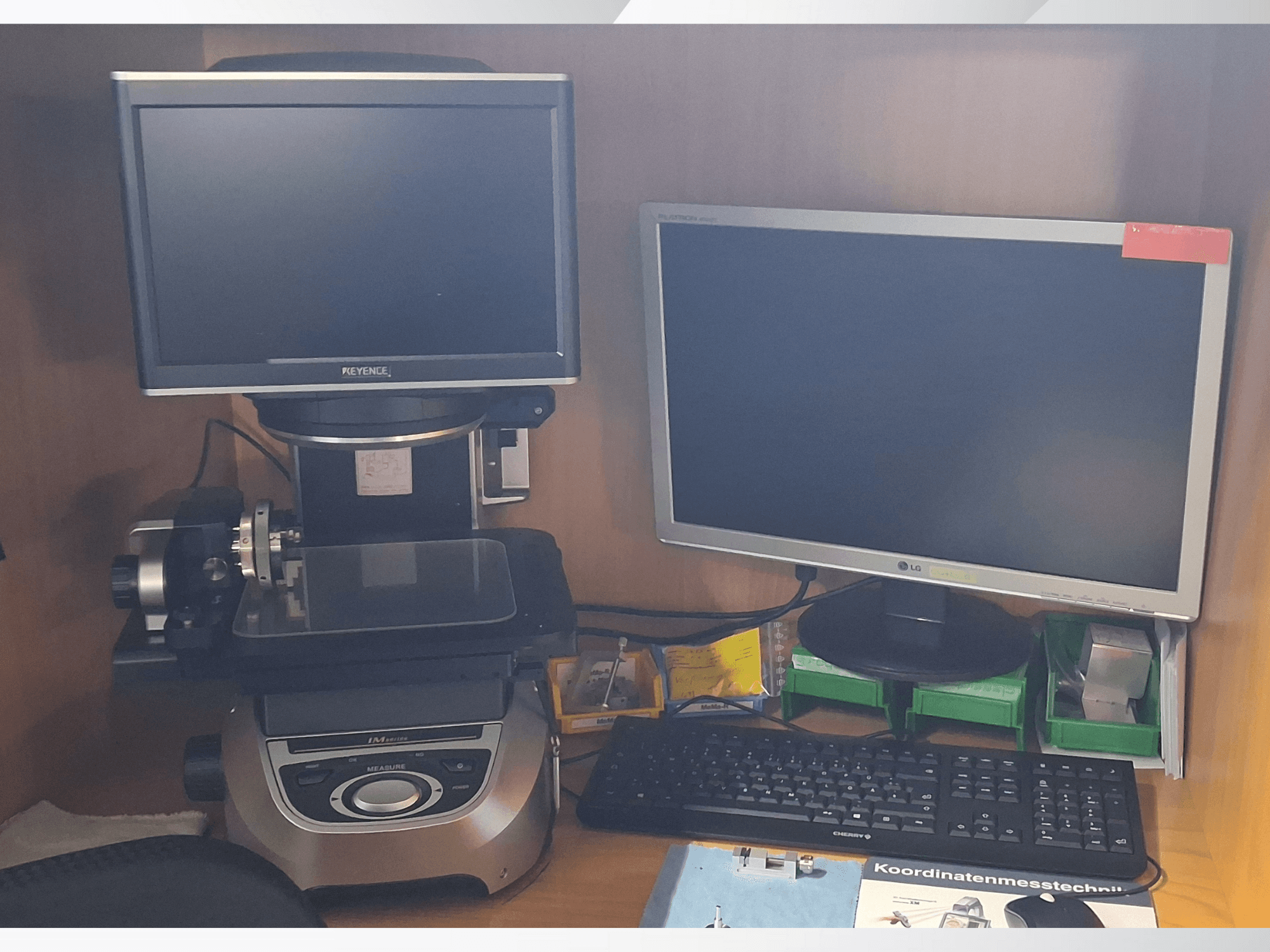 System pomiarowy Keyence z dwoma monitorami (jeden LG, jeden Keyence) i klawiaturą, widok z przodu.