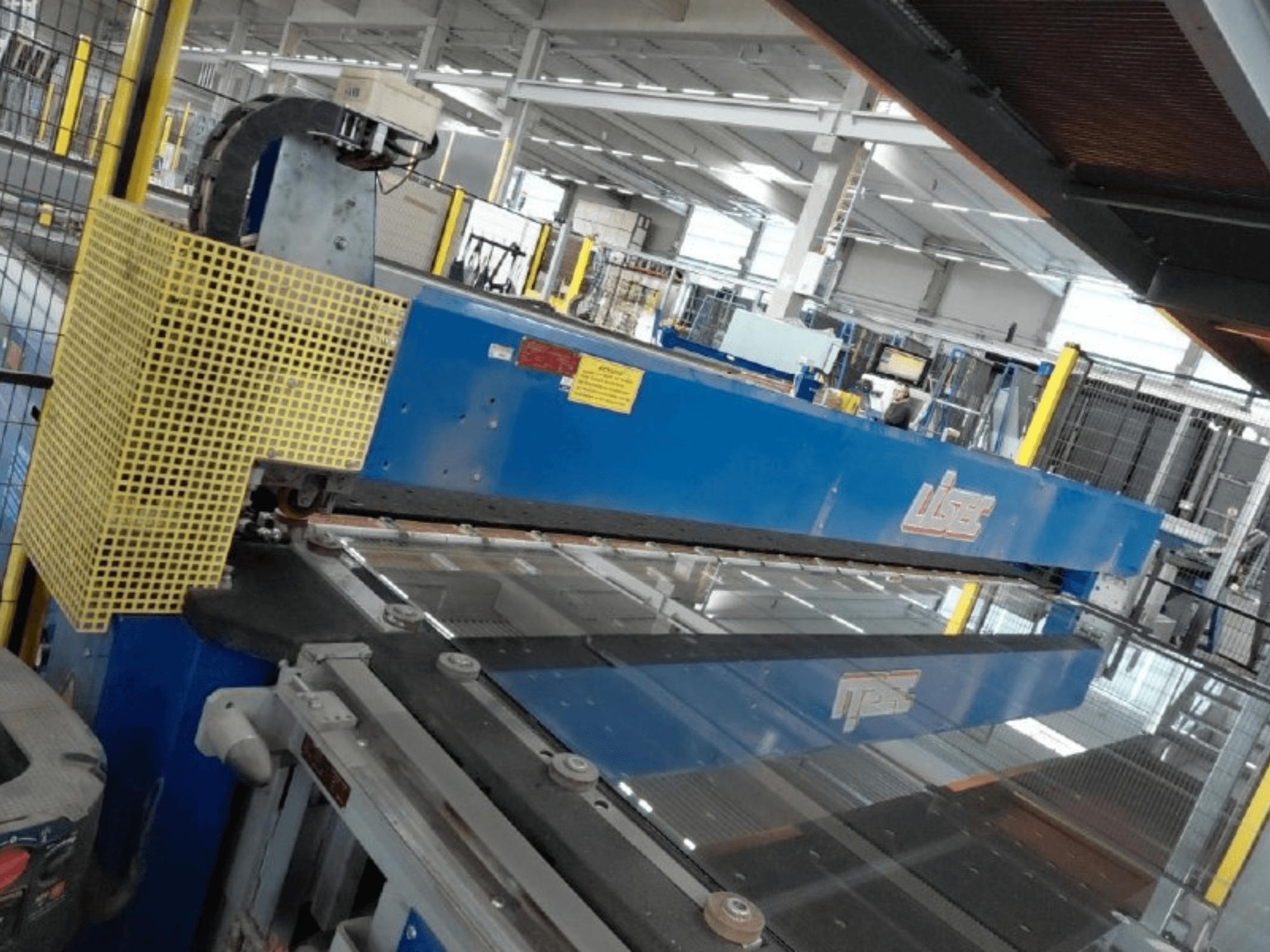 Widok z przodu linii do cięcia szkła laminowanego VSG i szkła float firmy LISEC, z niebieskim narzędziem tnącym i siatką ochronną.