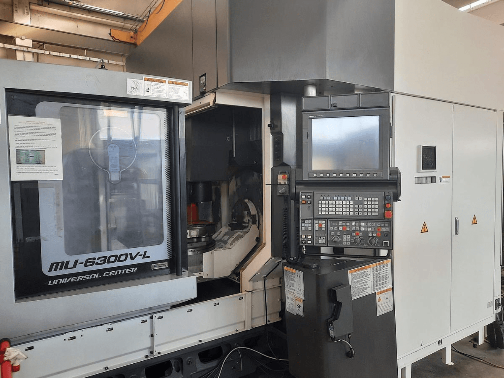 Maszyna MU-6300V-L Universal Center pokazana od przodu, z widocznym panelem sterowania, ekranem i instrukcją obsługi.