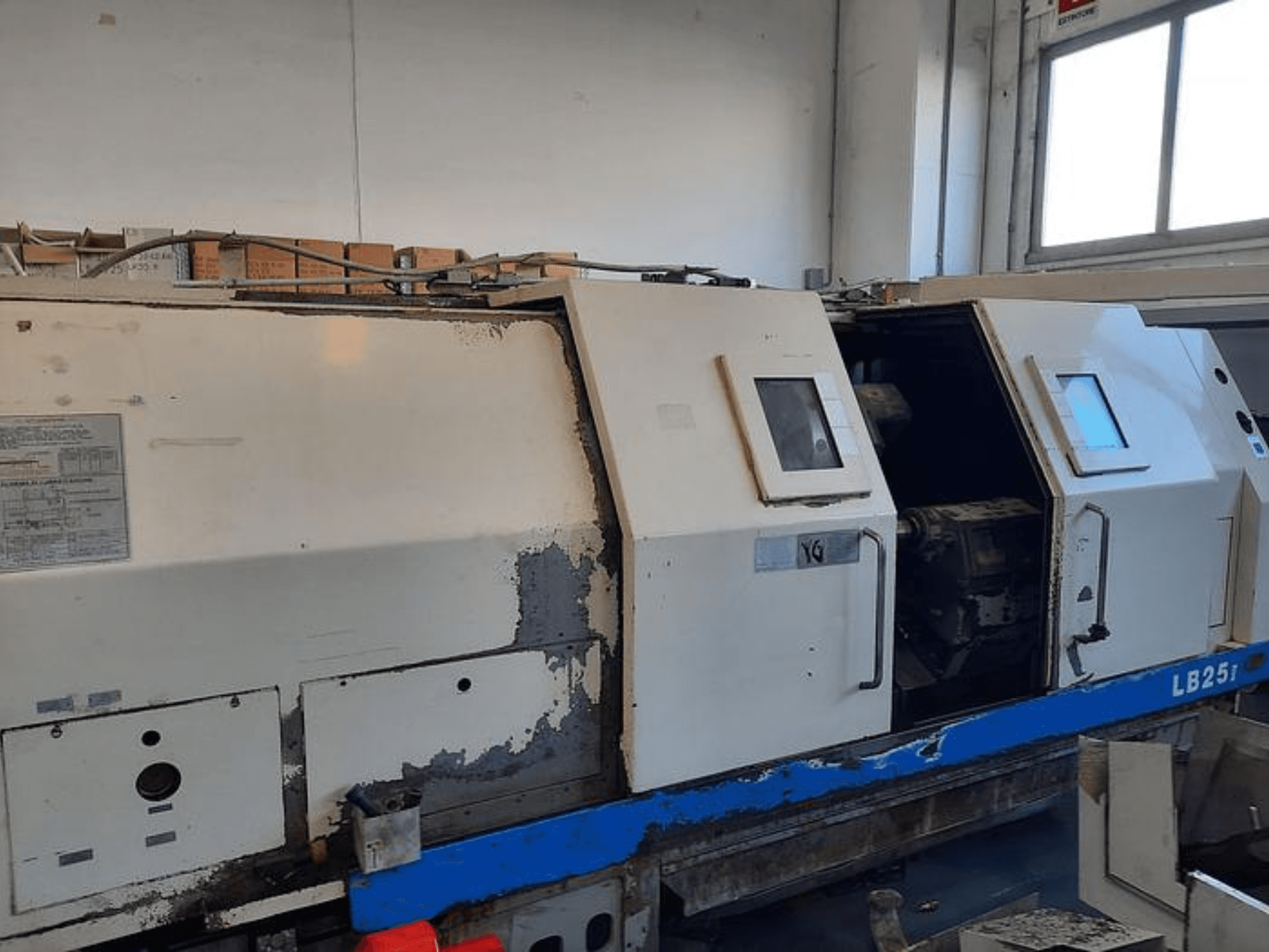 Używana tokarka LB251, widok z boku pokazujący zużyte elementy zewnętrzne, otwarty panel odsłaniający wewnętrzny mechanizm i elementy sterujące.