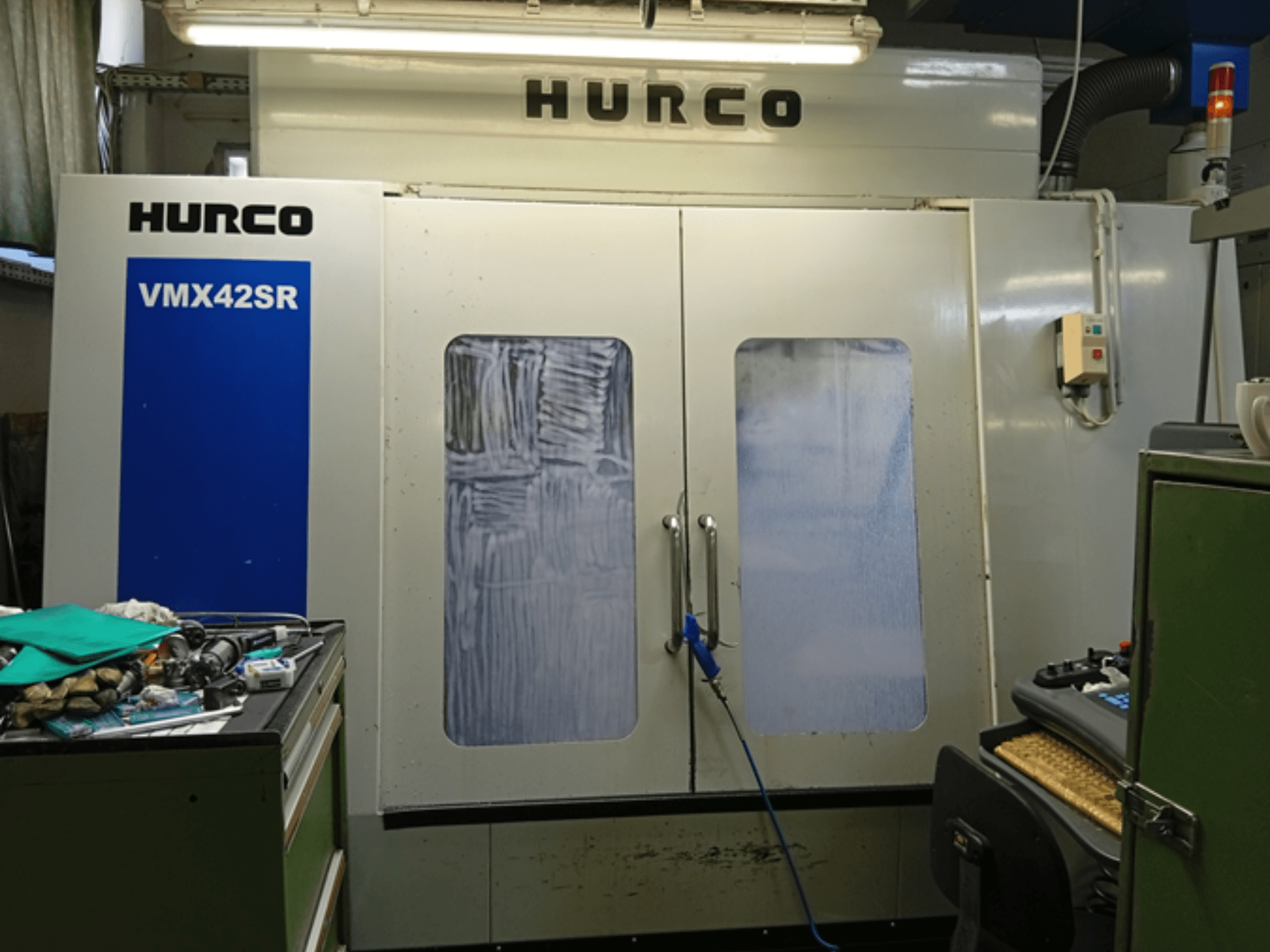 Pionowe centrum obróbcze Hurco VMX 42SR w widoku z przodu, z niebieskim panelem, interfejsem sterowania i czystą przestrzenią roboczą.