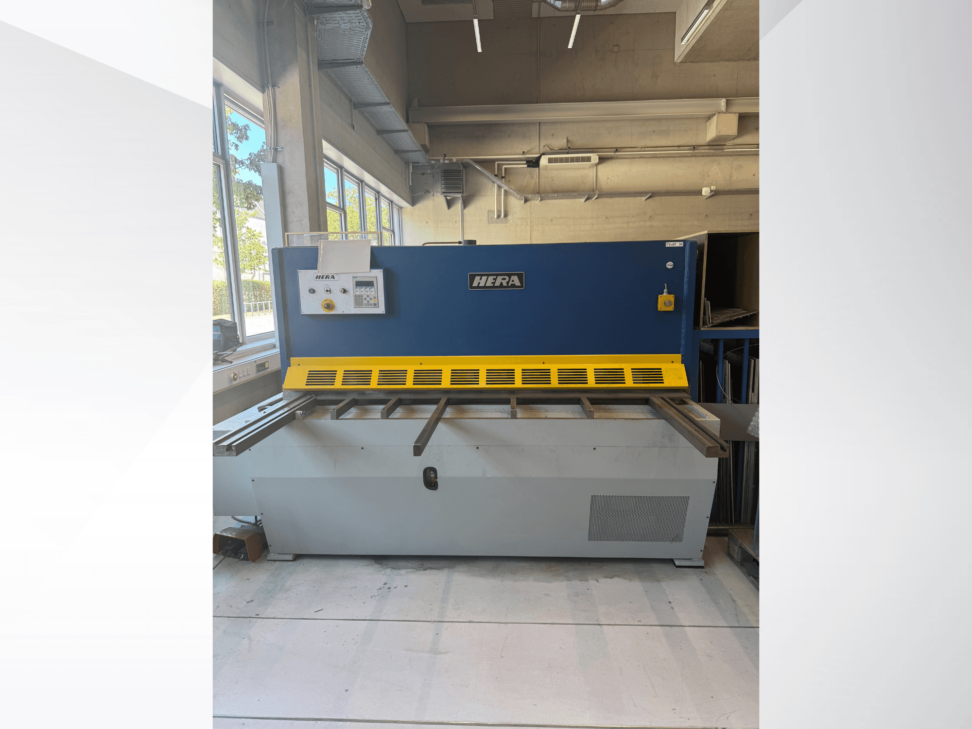Hydrauliczna nożyca HERA TS 2000x6 widziana z przodu, w niebiesko-żółtej kolorystyce, z panelem sterowania i stołem tnącym.
