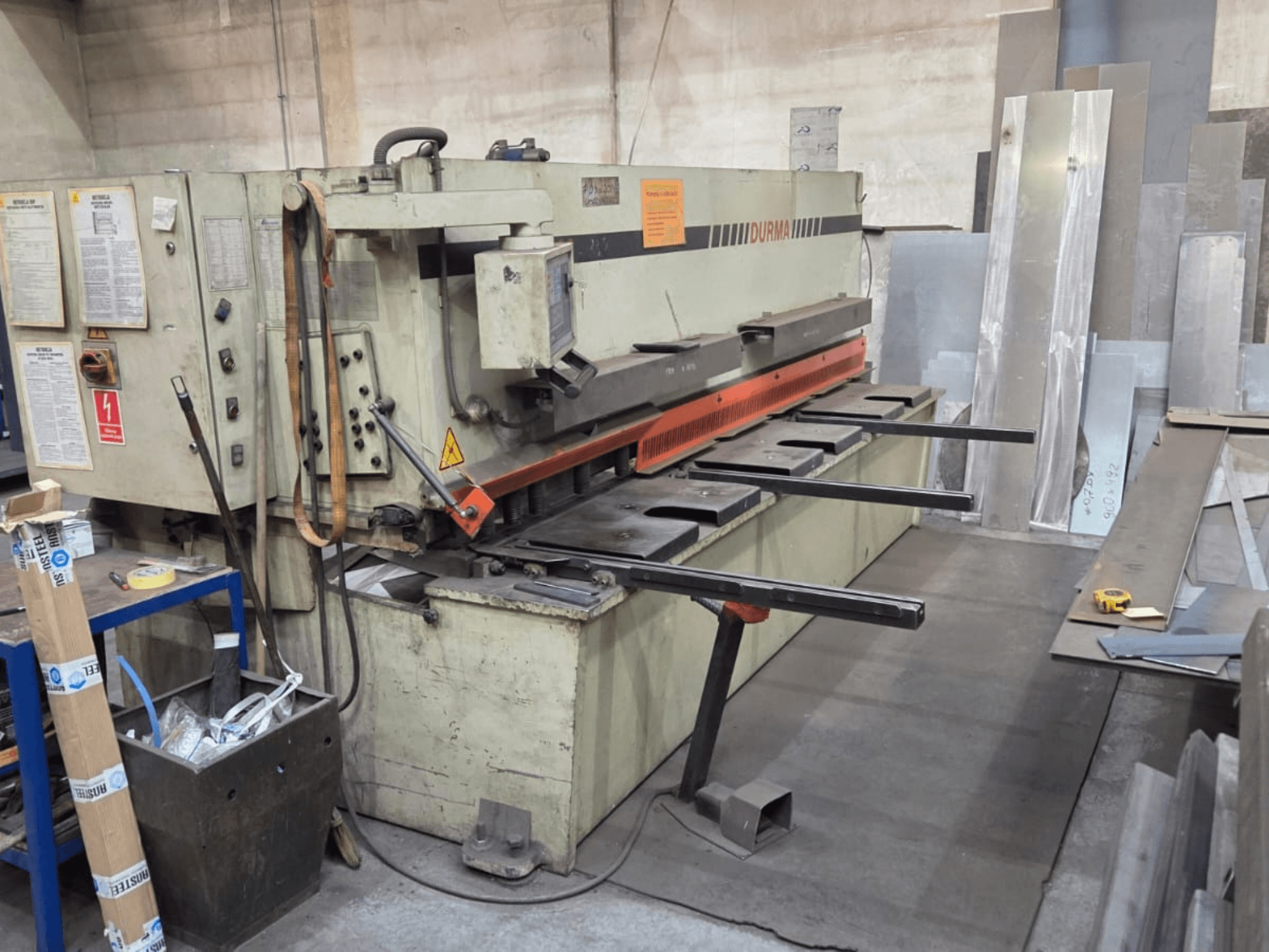 Nożyce hydrauliczne Durma SB 3060, widok z przodu, pokazujące elementy sterujące, ostrze tnące i blachy w obszarze roboczym.