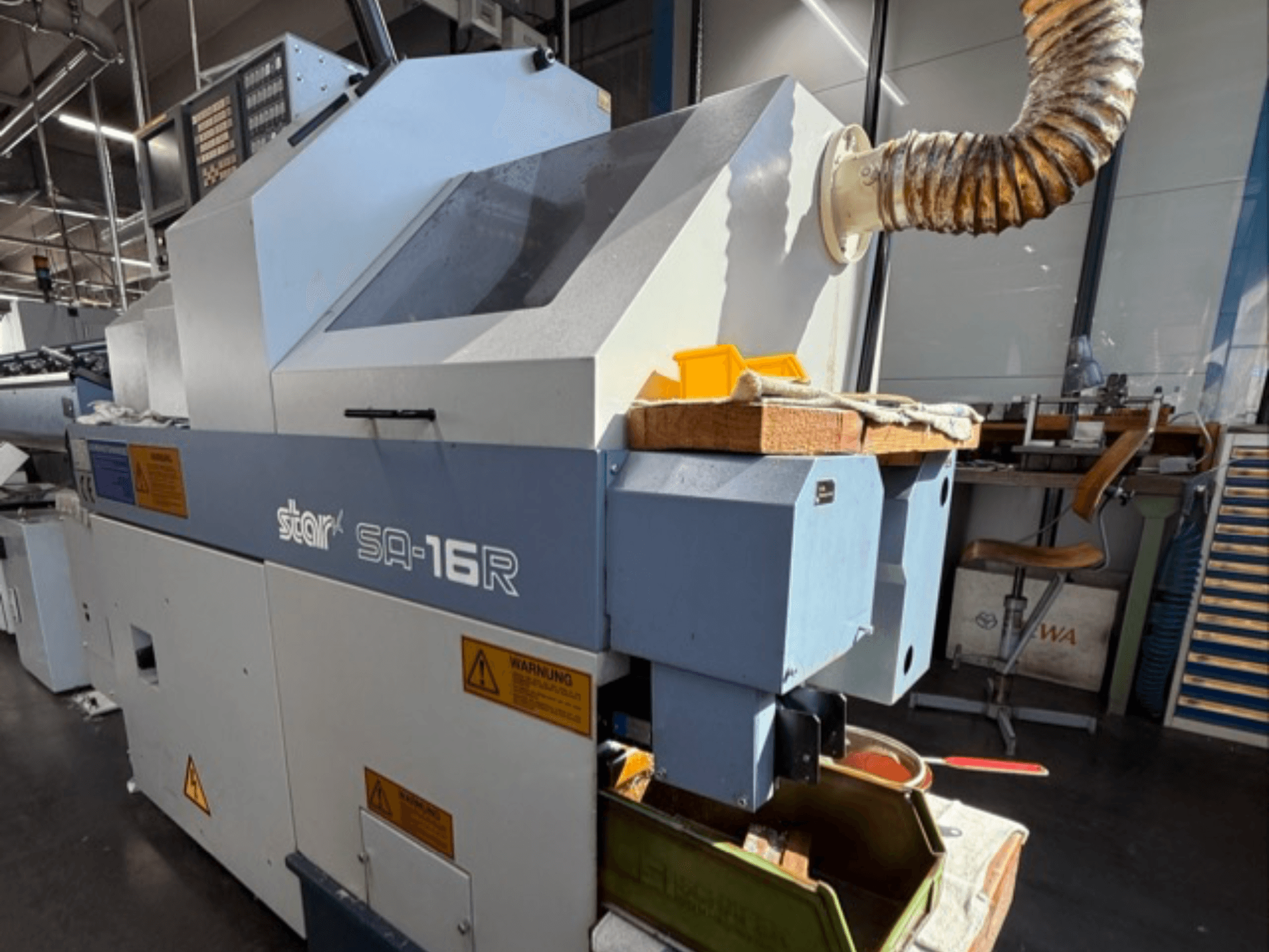 Maszyna Stark SA-16R widziana od przodu, ze zwężającym się otworem wydechowym i obszarem roboczym z żółtymi narzędziami i etykietami ostrzegawczymi.