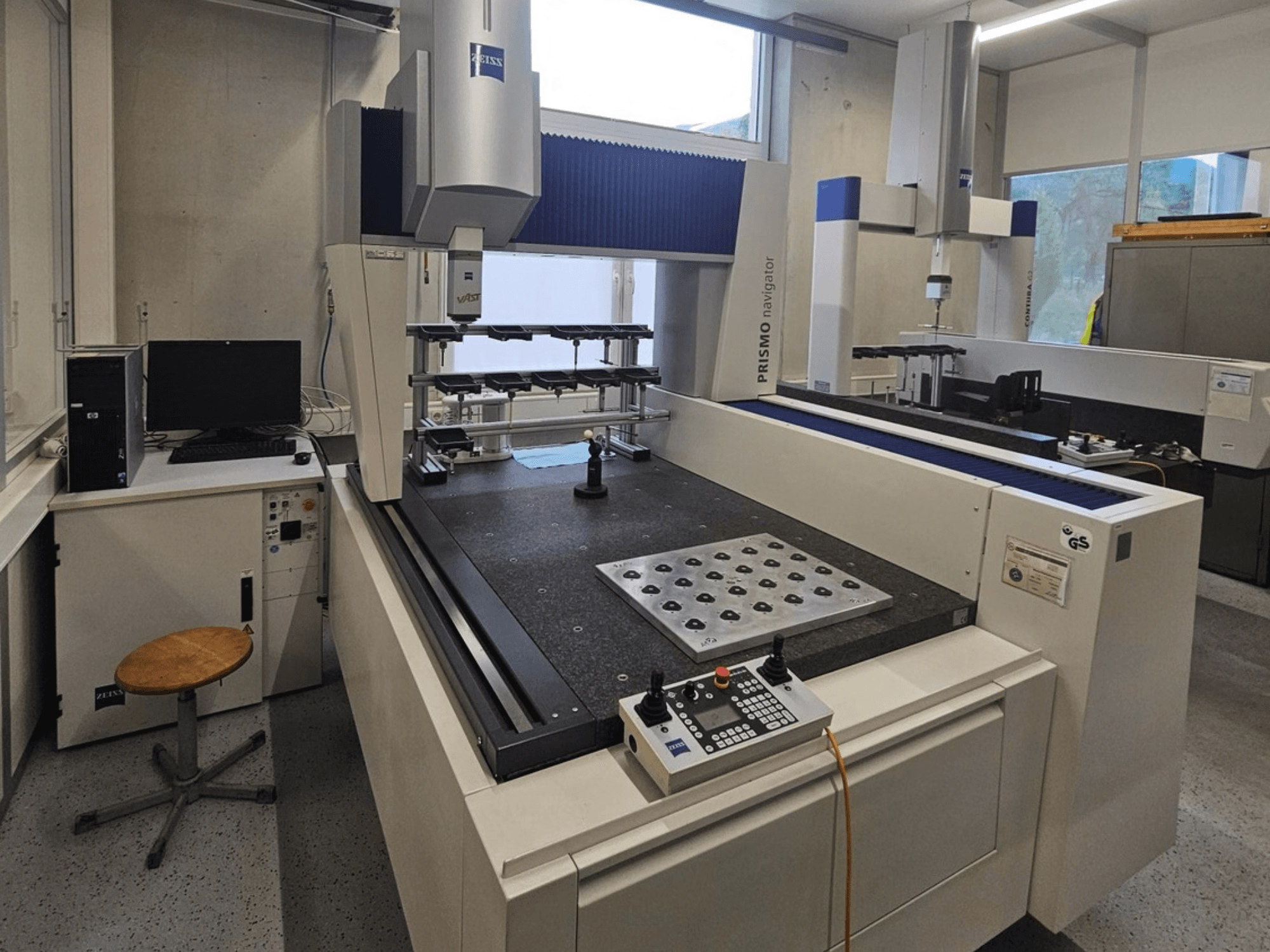 Maszyna CMM ZEISS Prismo Navigator 7 w laboratorium – widok z przodu przedstawiający panel sterowania, stół roboczy i monitor.