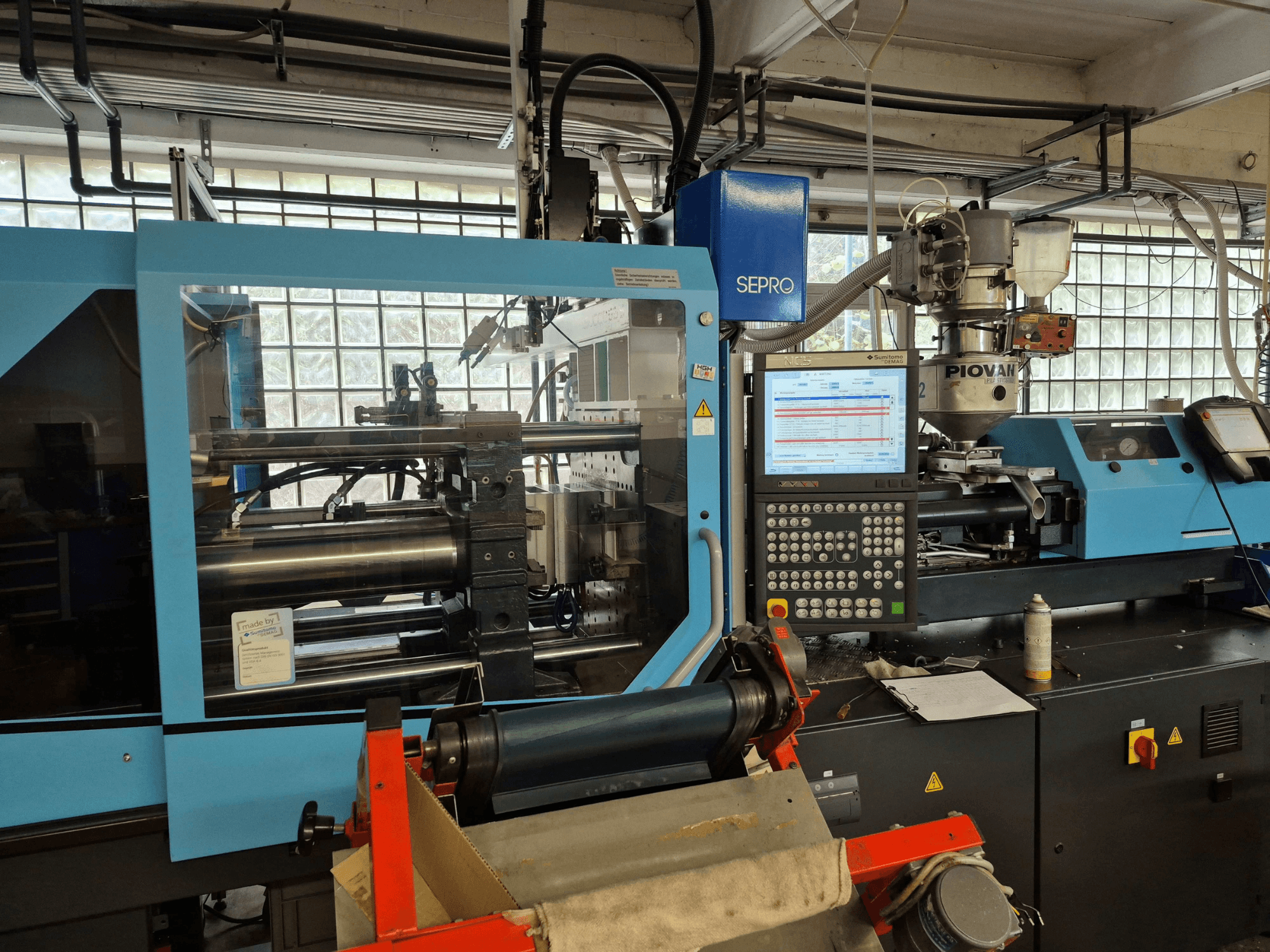 Hydrauliczna wtryskarka SUMITOMO SHI DEMAG Systec 120/470-430, widok z przodu z widocznym panelem sterowania i układem podawania.
