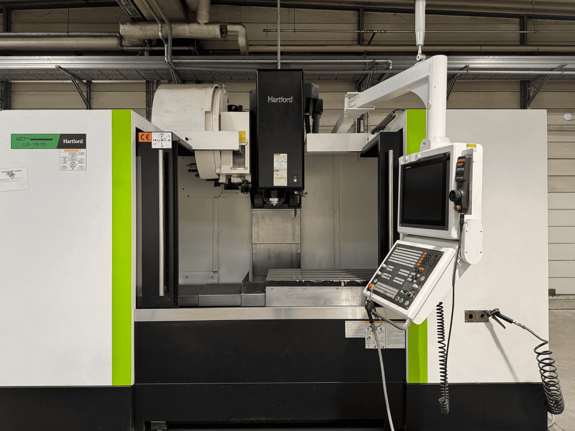 Pionowe centrum obróbcze Hartford LG 1570 TNC 640, widok z przodu; posiada panel sterowania i obszar roboczy z metalową podstawą.