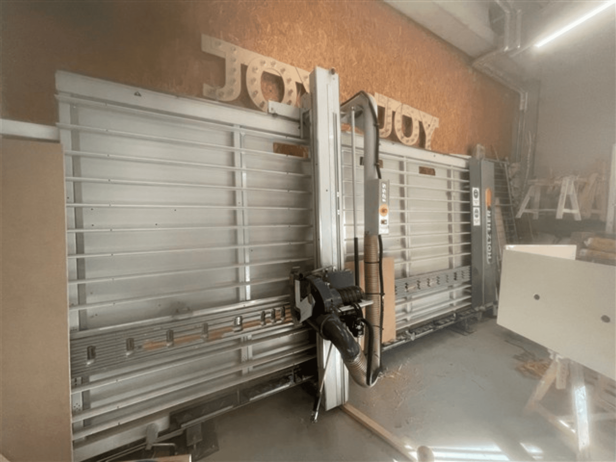 Pozioma pilarka panelowa marki Holz-Her, widok z boku, prezentuje tarczę pilarską, odsysanie pyłu i schowek.