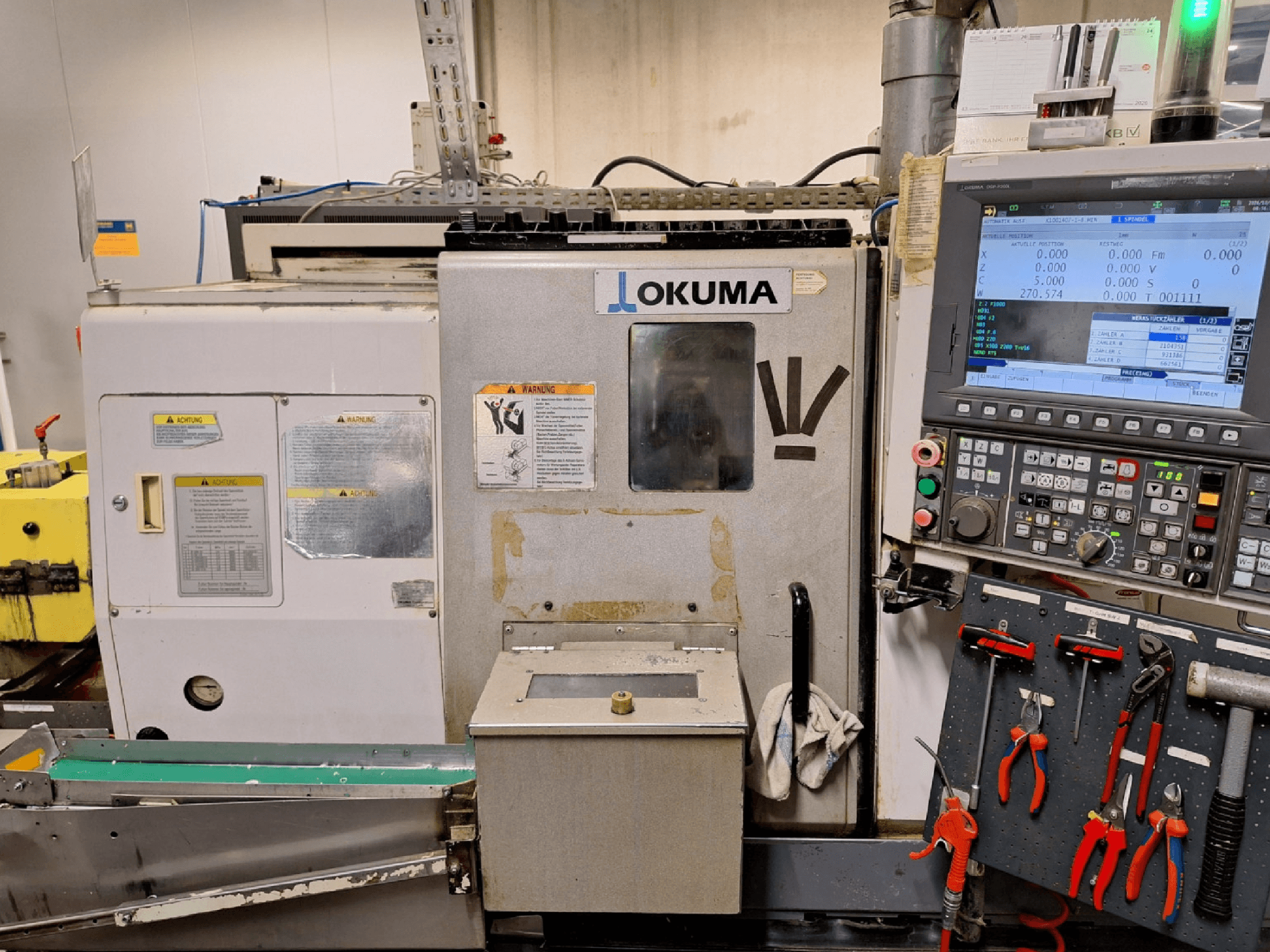 Pozioma tokarka Okuma LB200-MW, widok z przodu, z widocznym z boku panelem sterowania i narzędziami.